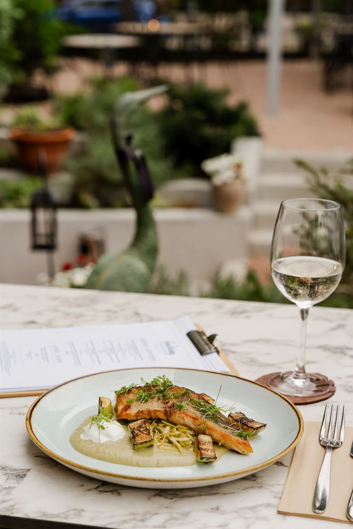 Roasted pike perch fillet with butter squash textures and a glass of chilled white wine in the garden of Andrássy Garden.