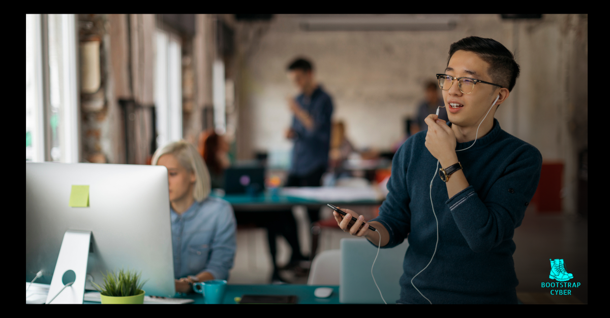 Man talking on cellphone in busy, modern office space, working on a cybersecurity sales deal