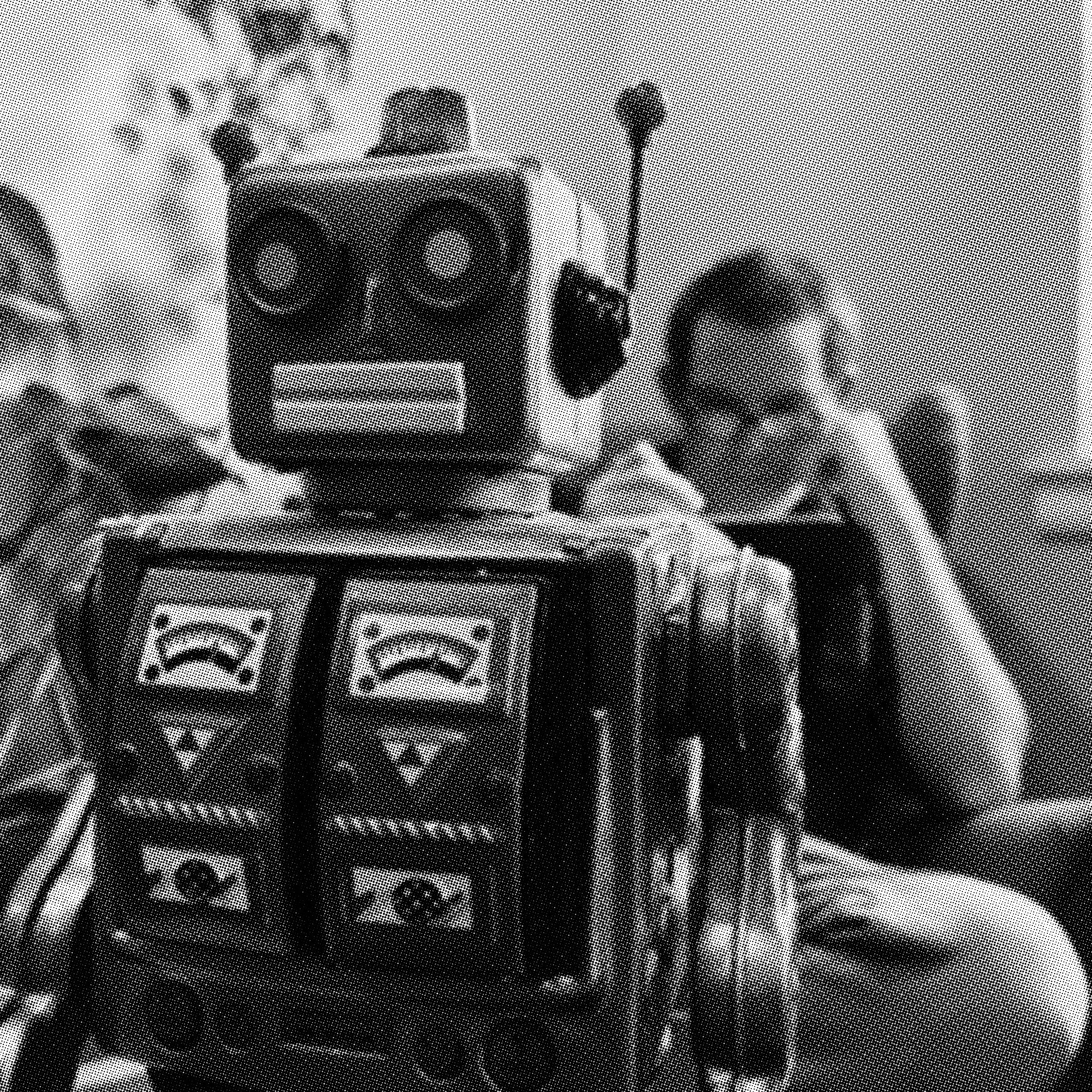 Retro toy robot in foreground with person reading in background.
