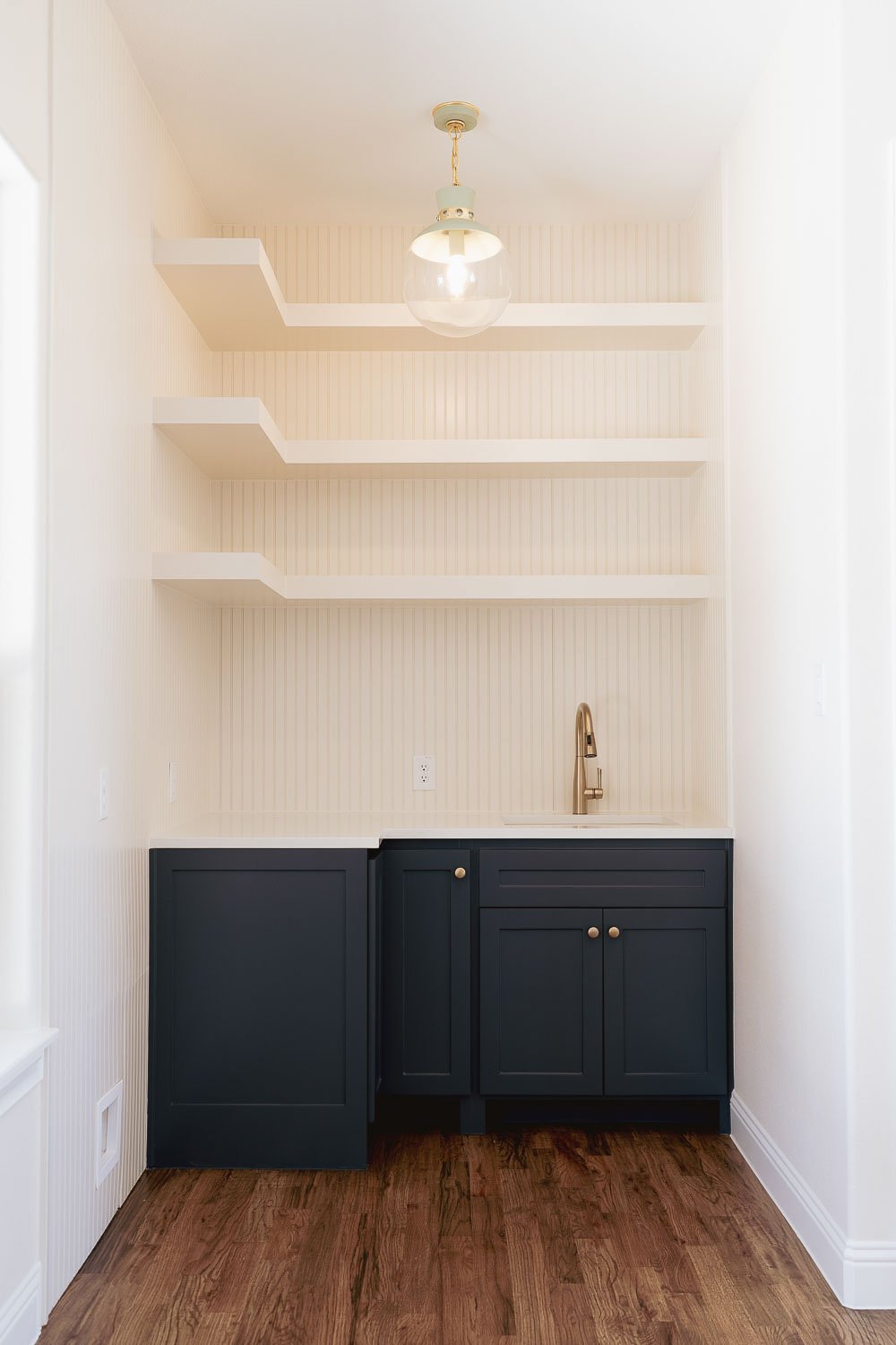 Utility room with gold sink and navy cabinets.