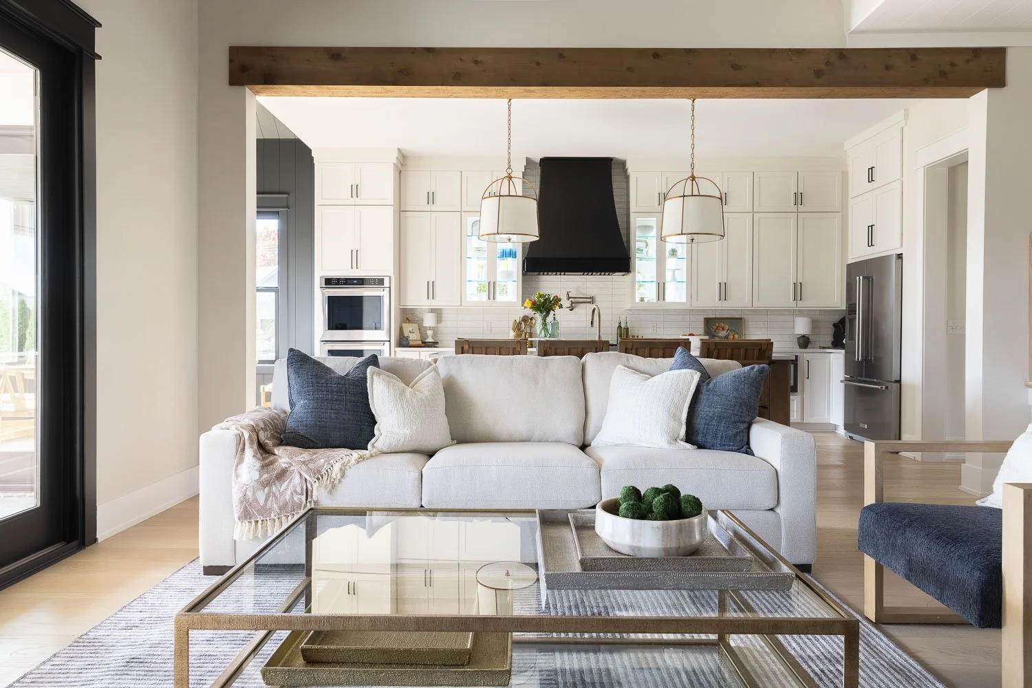 Timeless interior design family room with warm paint tones, white linen sofas, navy blue accent pillows, and custom built-in cabinets in the background showcasing farmhouse interior design style. 