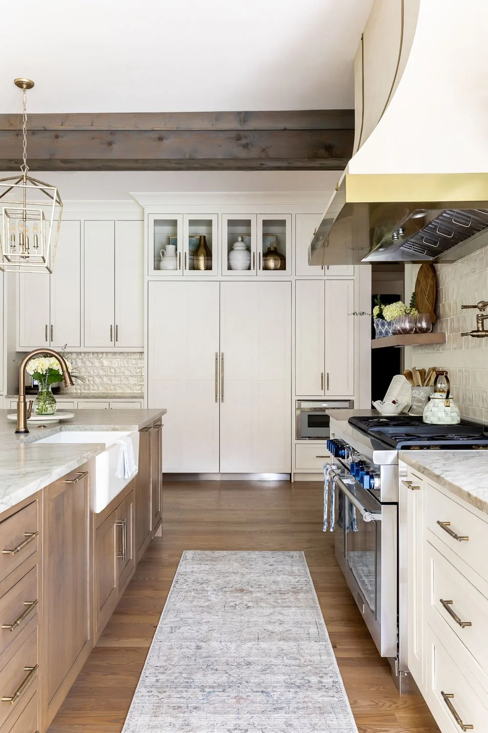  imeless interior design kitchen featuring open concept floor plans, gray interior paint on lower cabinets, custom built-in cabinets, farmhouse sink, and warm wood floors reflecting trends for interior design. 