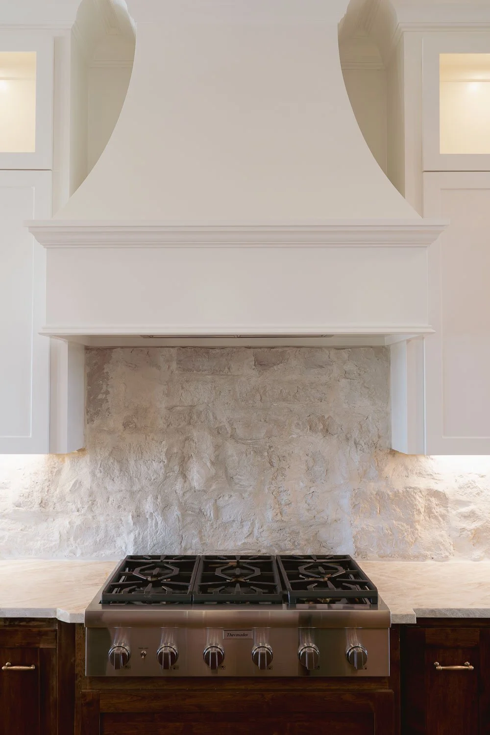  Farmhouse interior design kitchen with custom built-in cabinet.s, a natural stone backsplash, warm paint tones, and a professional range reflecting timeless interior design and trends for interior design 