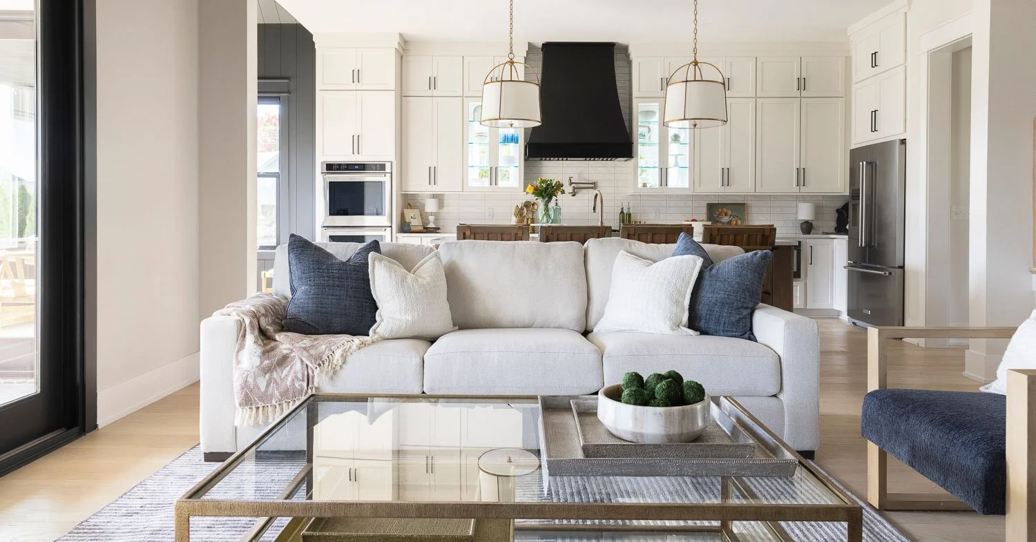Trends for interior design living room featuring warm paint tones, open concept floor plans, farmhouse interior design-inspired décor, white sofas with layered textures, and a black statement range hood.