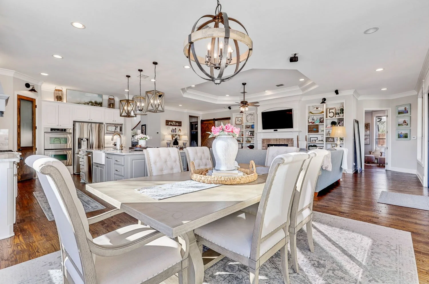 Farmhouse dining room design with chandelier lighting and open concept floor plan connecting to living spaces.