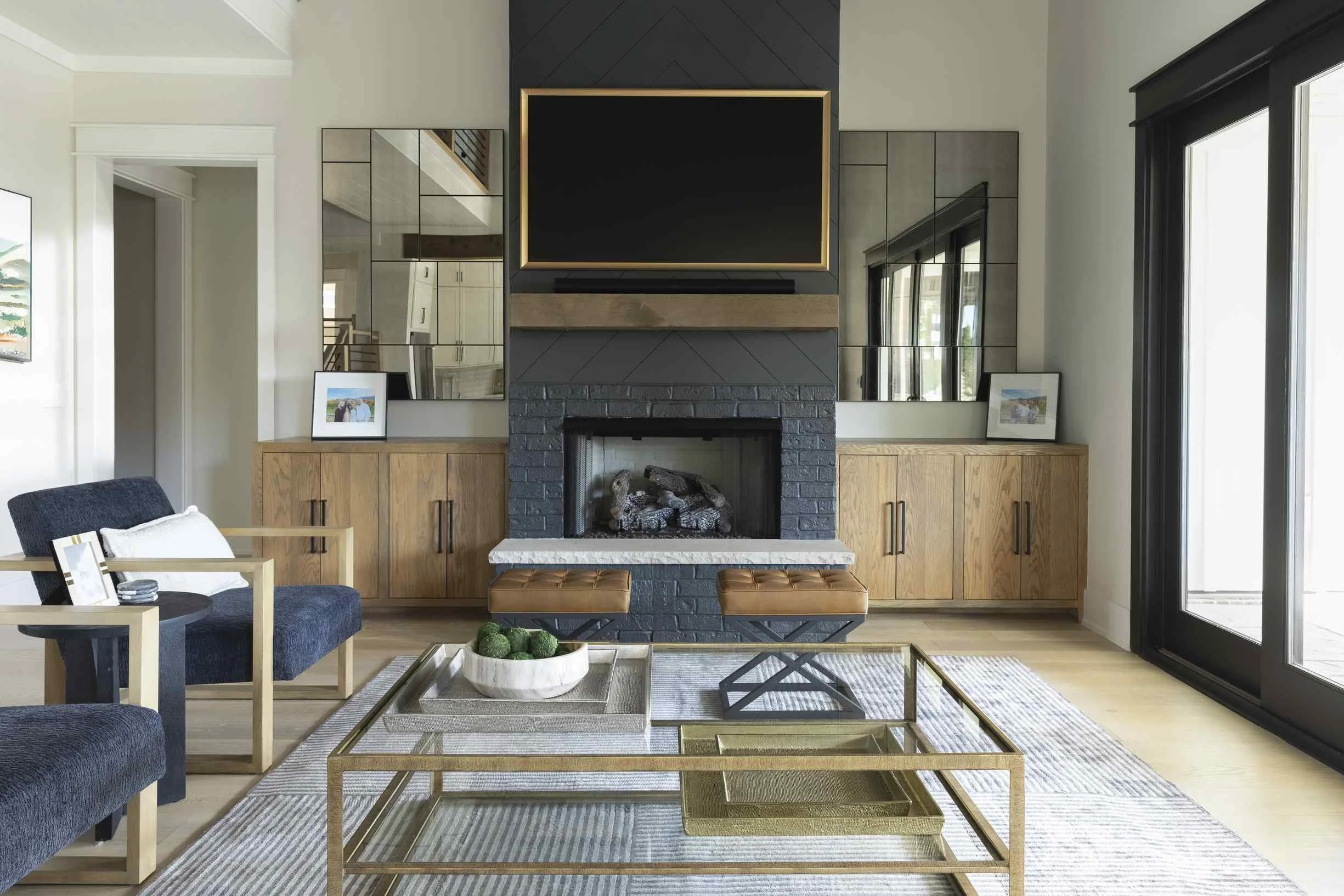 Interior decorating tips for living room with dark painted brick fireplace, flanking oak media cabinets, antique mirror panels, and gold coffee tables.
