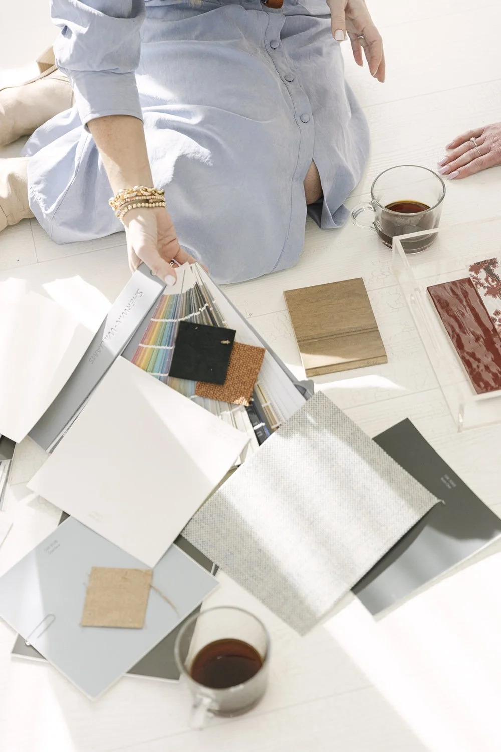 Paint fan deck, fabric swatches, a wood finish sample, and red tile spread out during the interior design selection process
