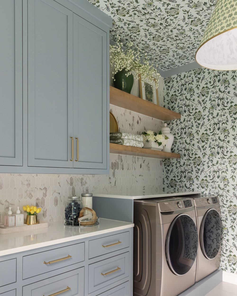 Laundry room by an interior designer near Nashville with blue-gray cabinets, brass pulls, and bird-and-floral wallpaper