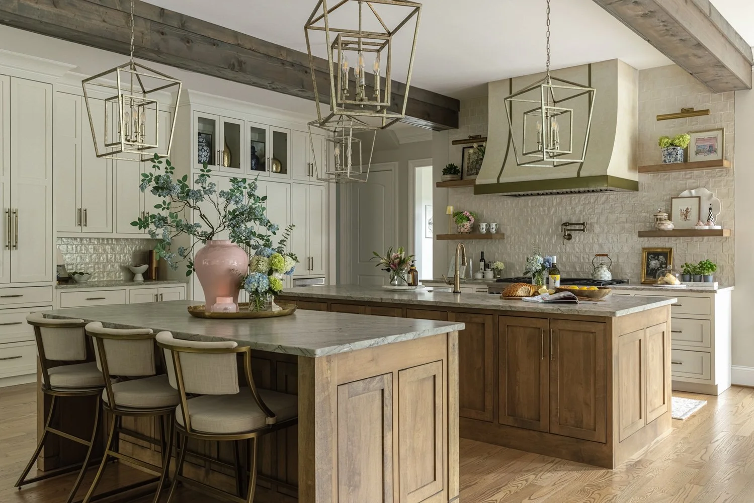 Kitchen with two stained wood islands, lantern pendants, a plaster range hood with brass straps, and exposed wood beams
