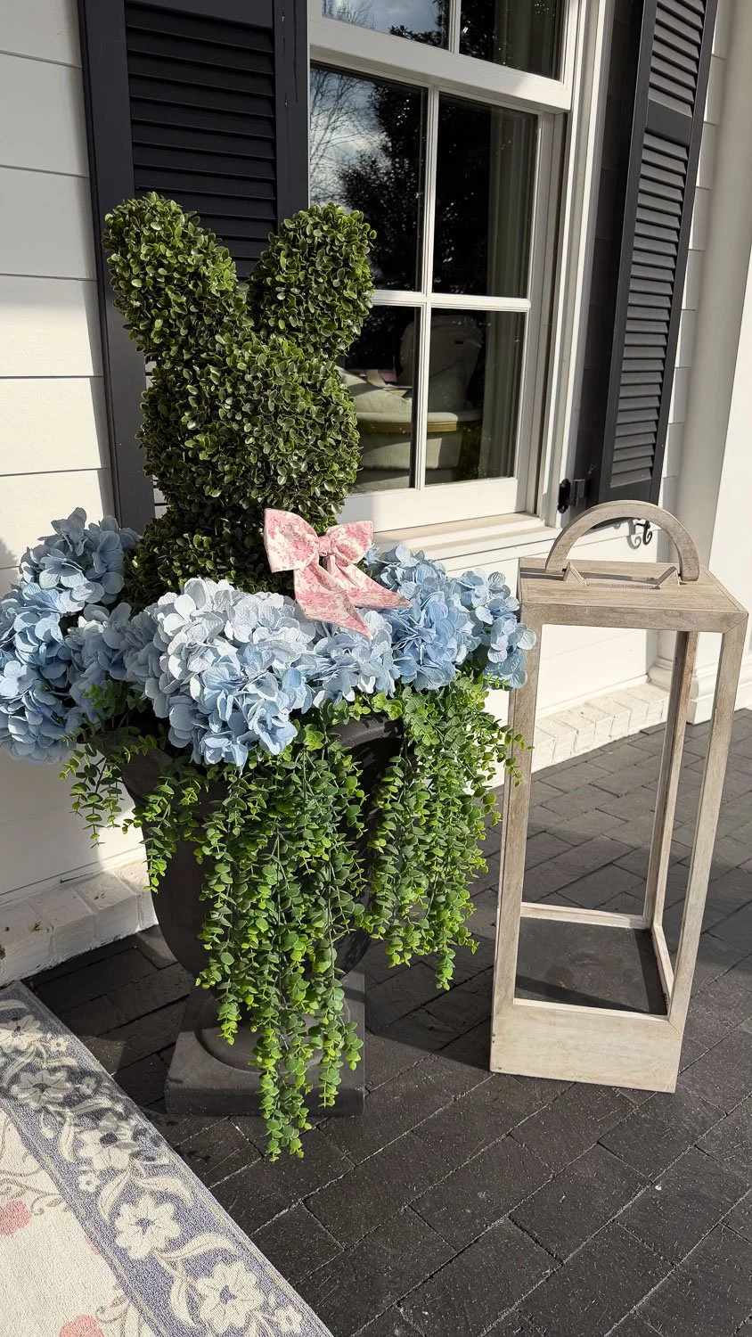 Spring decorating details on a classic front porch with cascading greenery and blue hydrangeas.