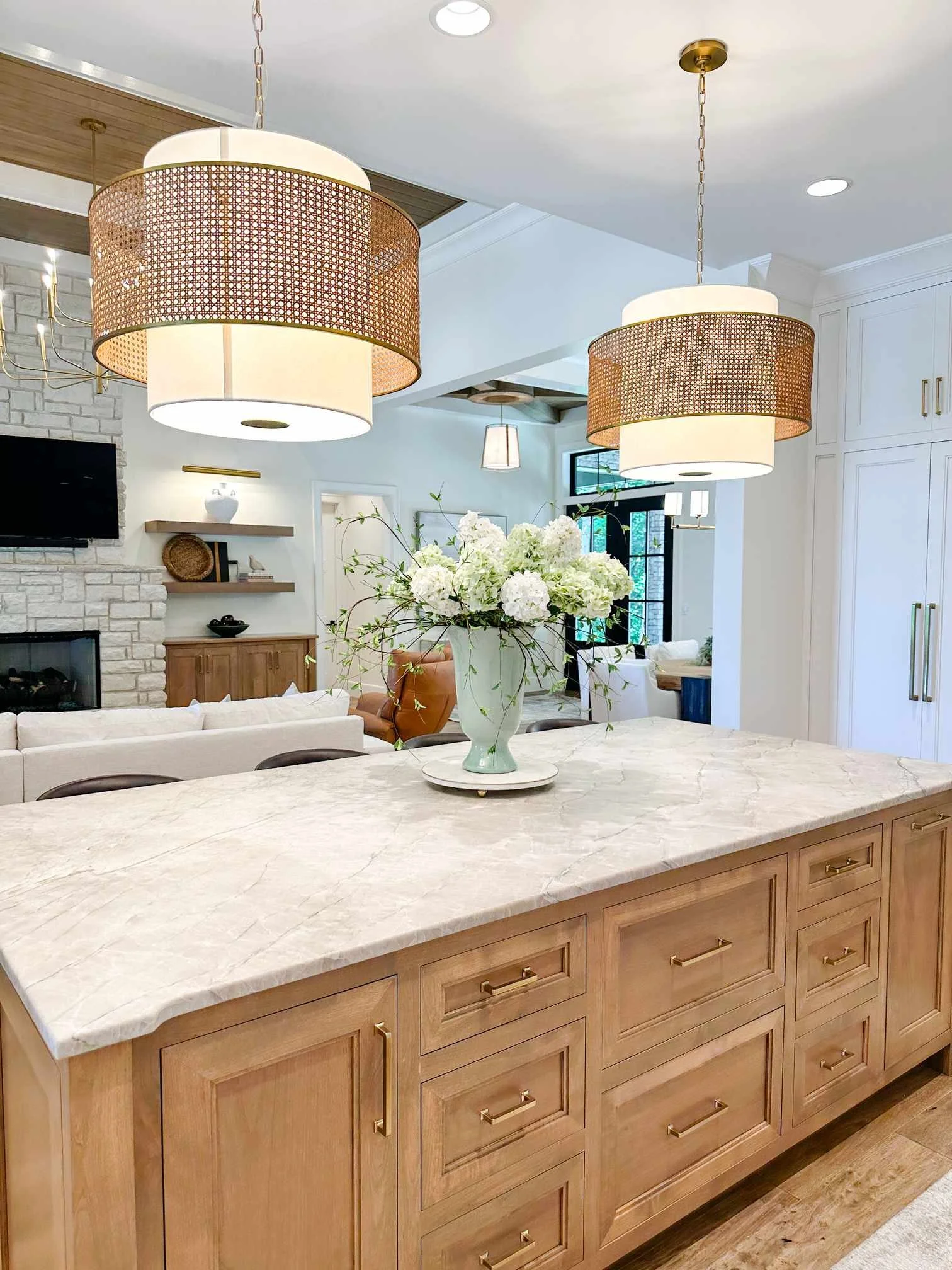 Light fixture upgrades: oversized rattan drum pendant lights over white oak kitchen island with marble countertop.