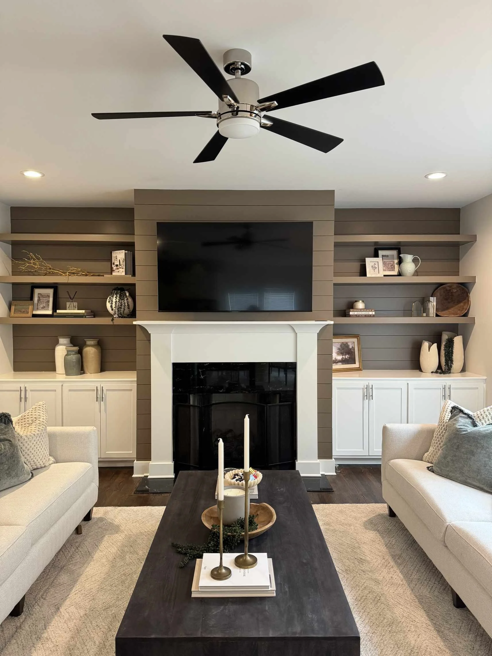 Interior decorating tips for living room with shiplap fireplace surround, built-in shelving with curated decor, and cream sofas.