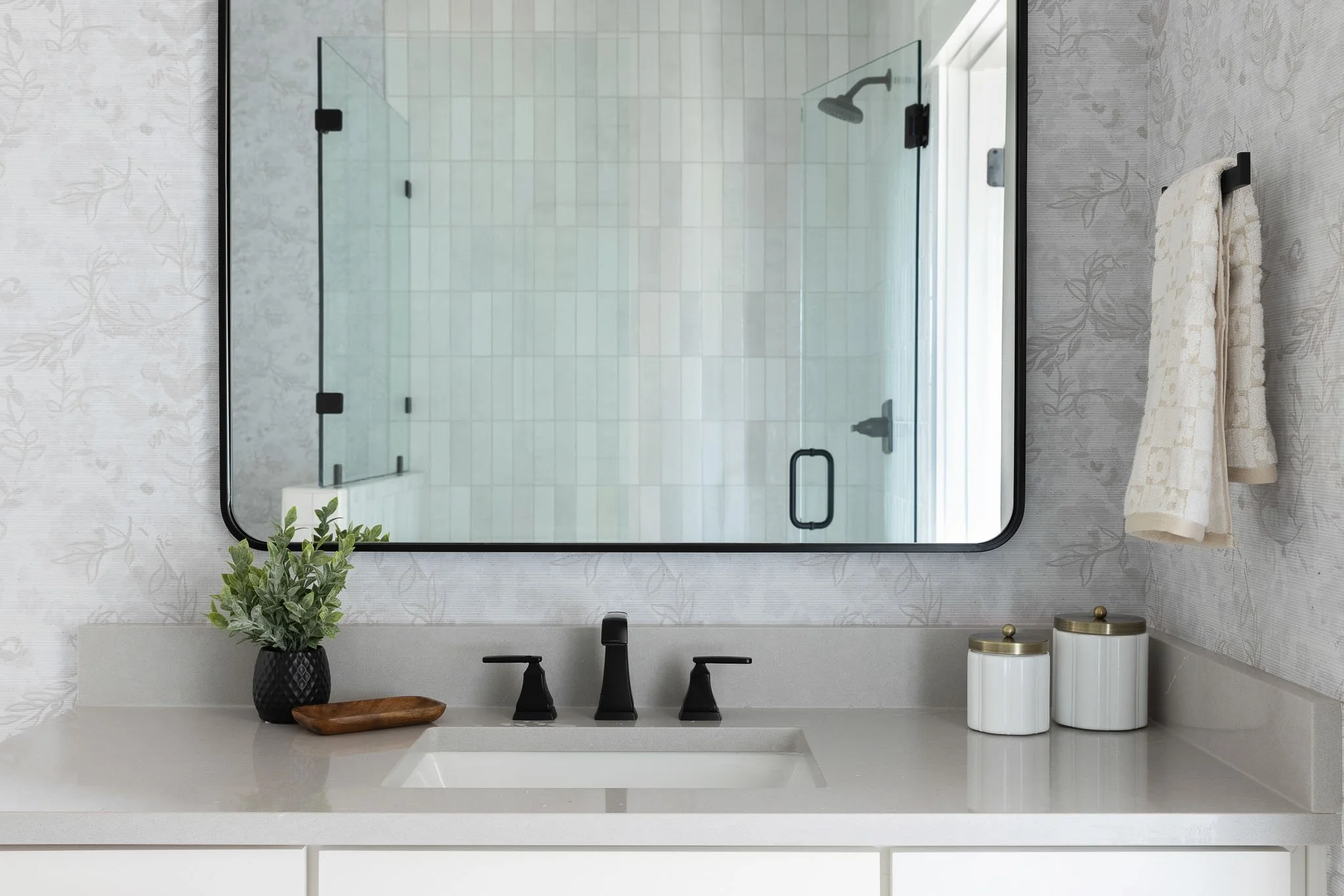 Clean, decluttered bathroom with coastal-inspired vanity mirror, simple styling, and organized countertop.