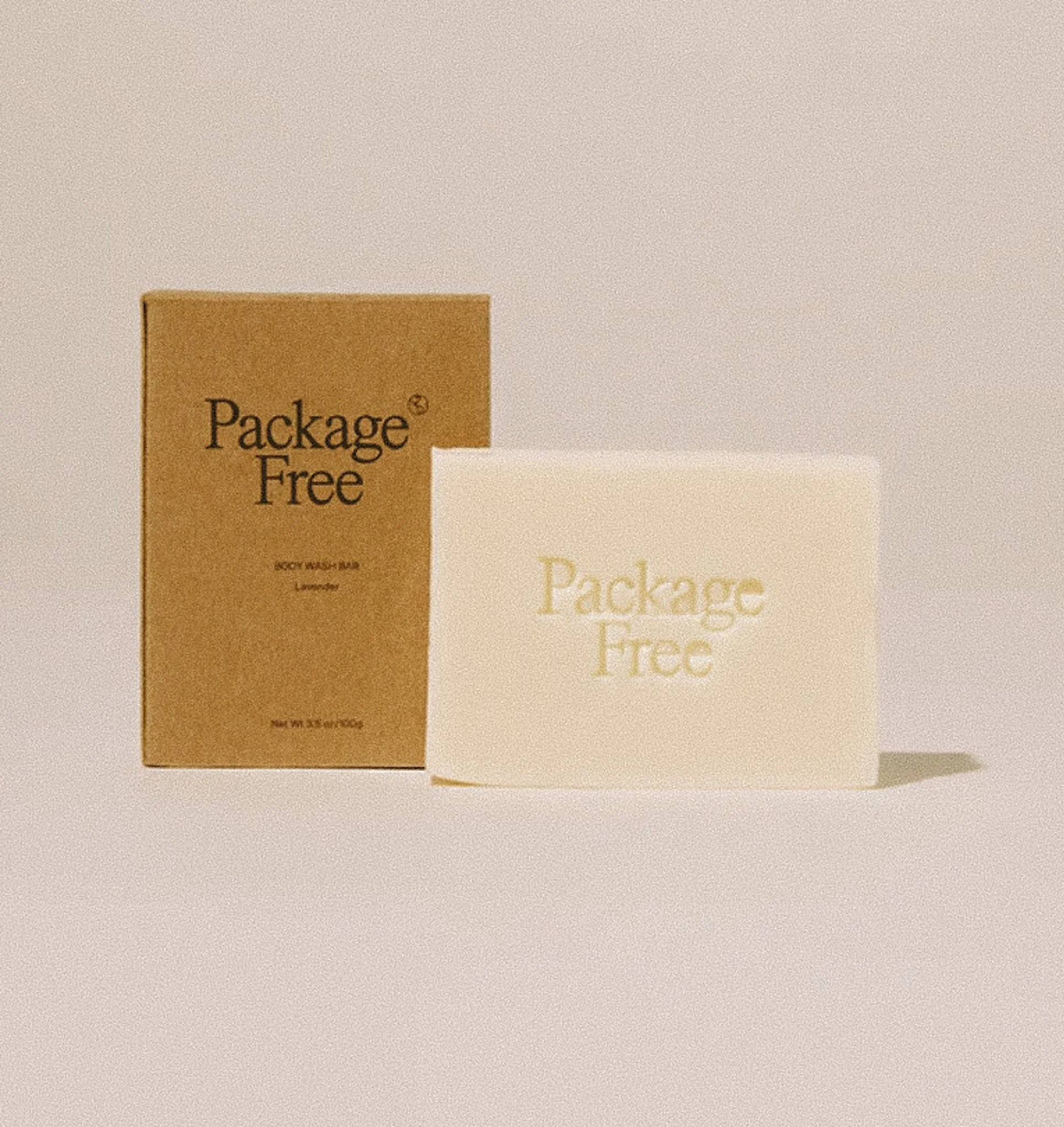 A bar of soap with the words "Package Free" embossed on it next to a brown cardboard box with the same text, indicating it is "not soap" and lemon scent, on a neutral background.