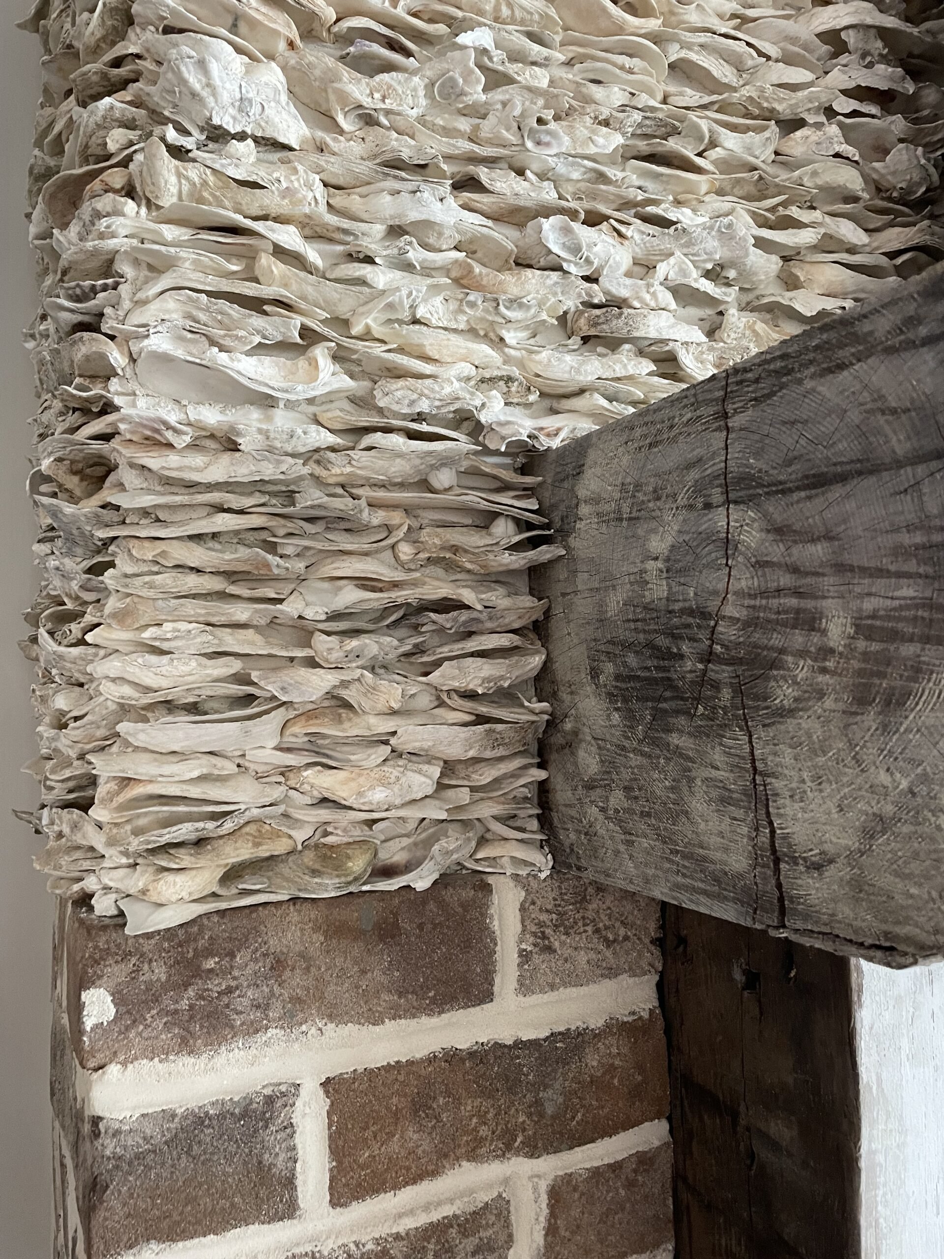Close-up of dried fish hung on a wooden beam above a brick fireplace.