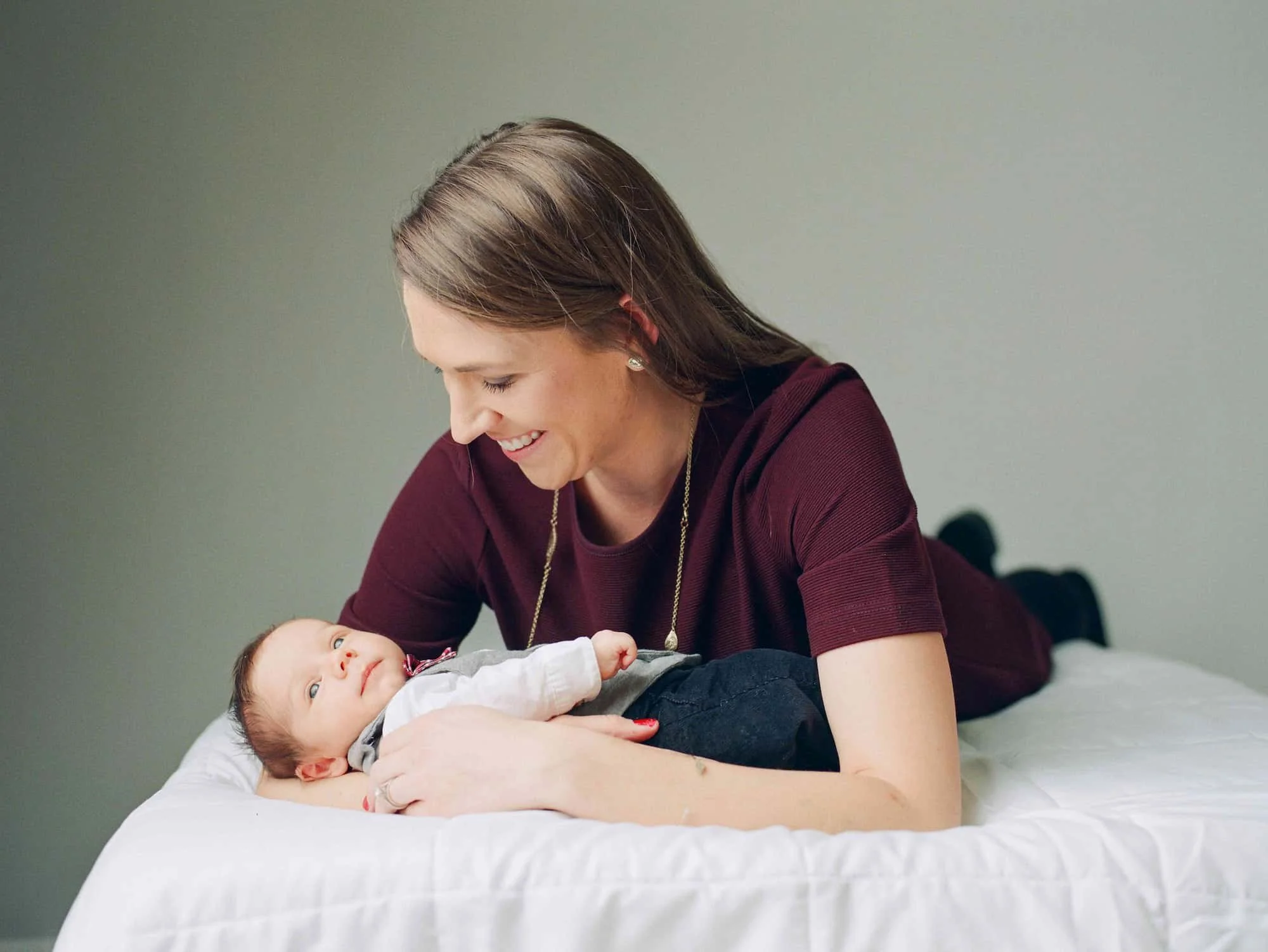 Newborn portrait of mom and her baby boy laying on a bed