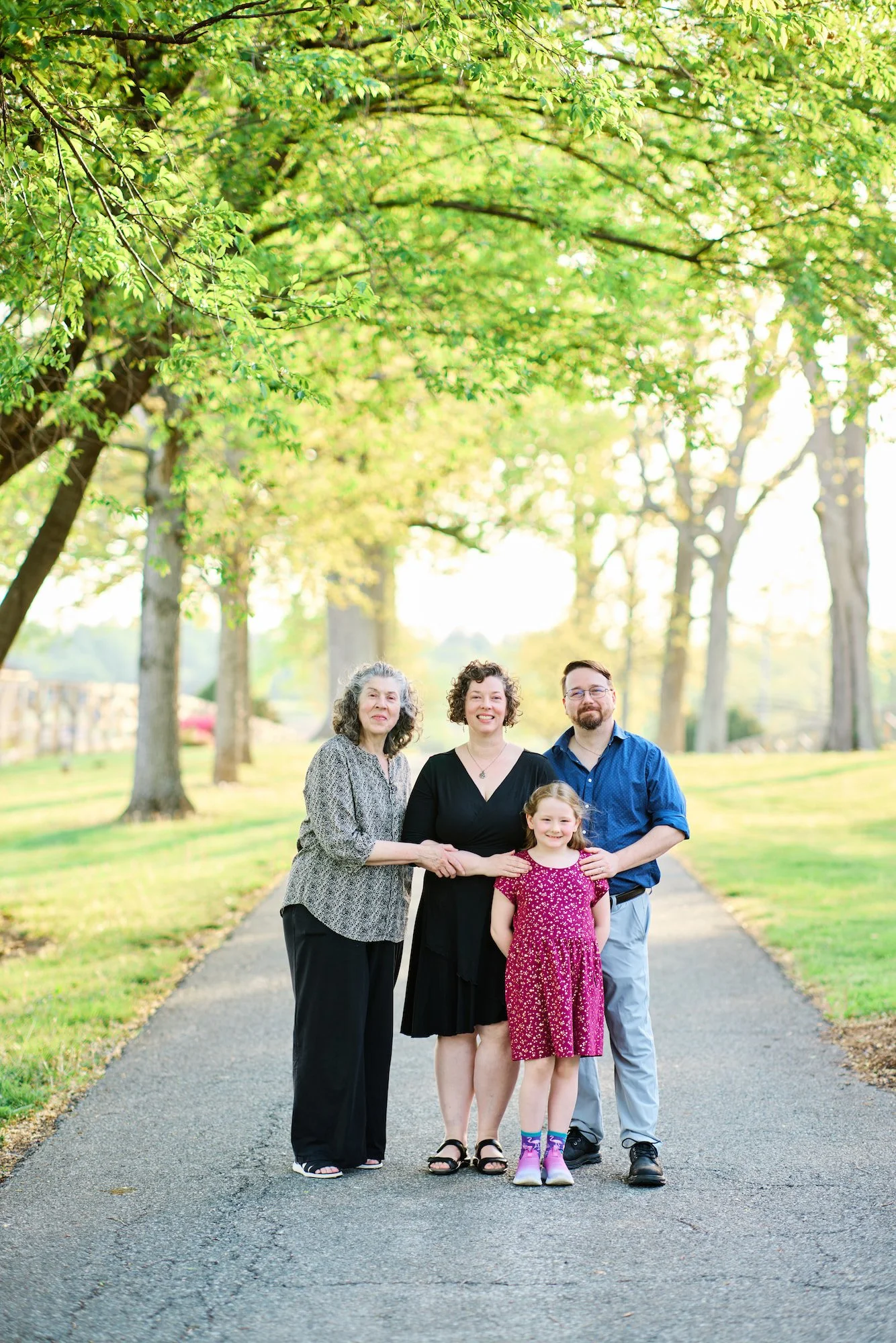 Portrait of a family on a tree lined road with golden hour sun coming in behind them