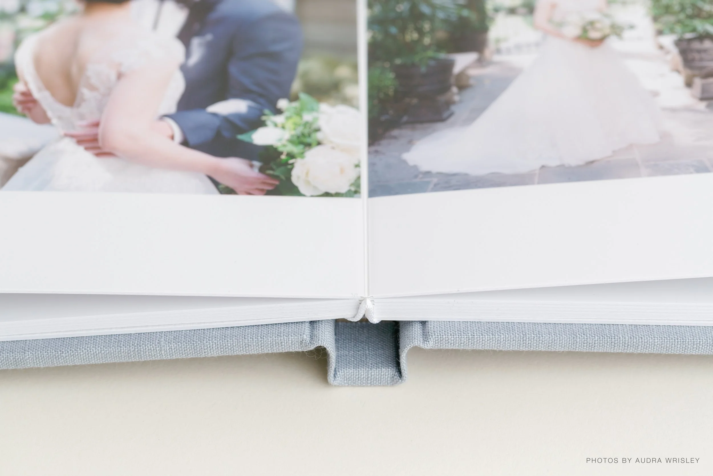 An open wedding album showing photographs of a bride and groom and a wedding dress, with a soft light background.