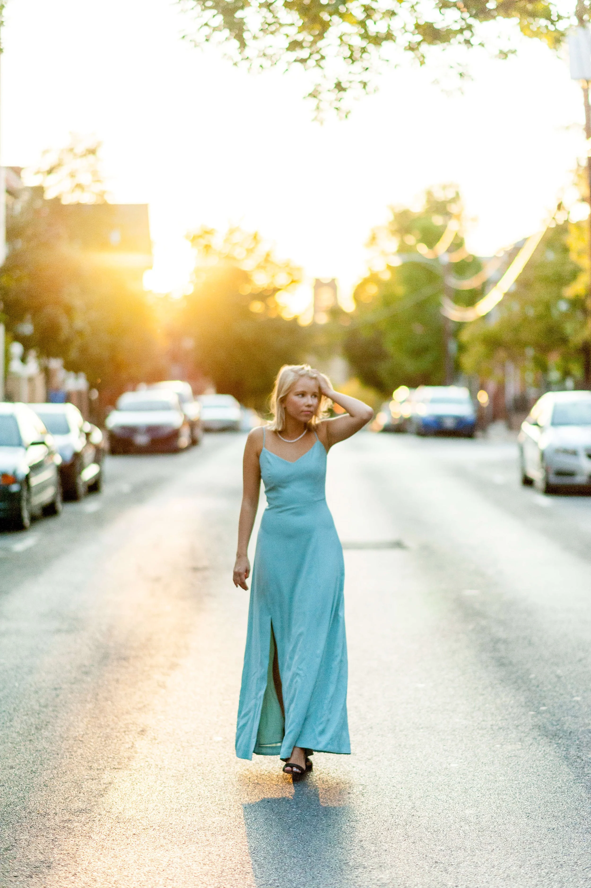 Senior portrait of a blond girl wearing a blue dress walking in the street