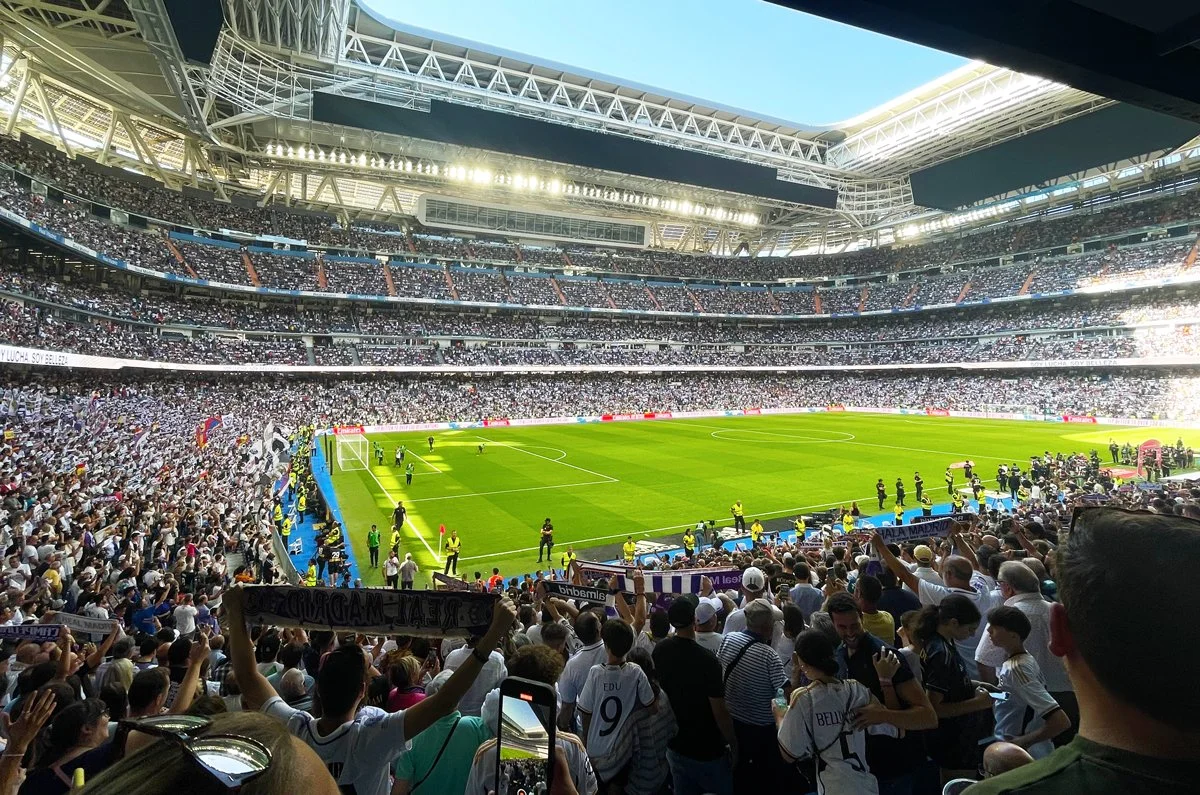 Vista panorámica del interior del estadio Santiago Bernabéu durante un partido con las gradas completamente llenas.
