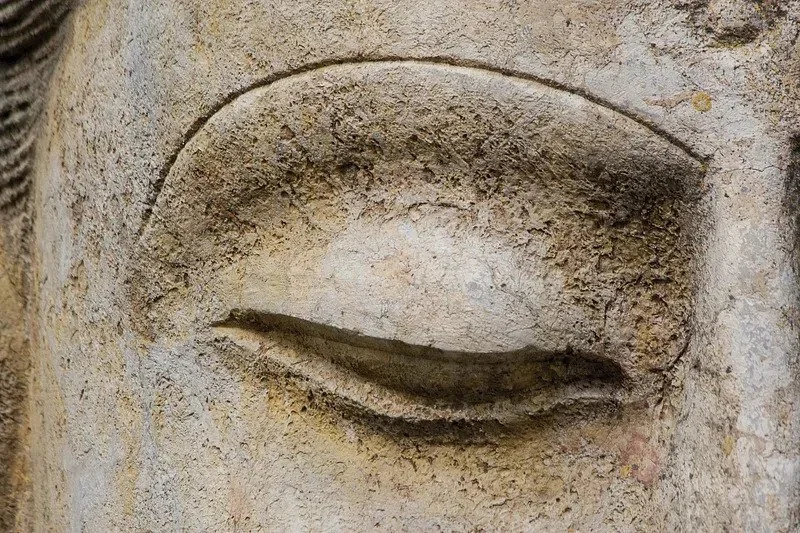 Close-up of an ancient stone sculpture of a winking eye.