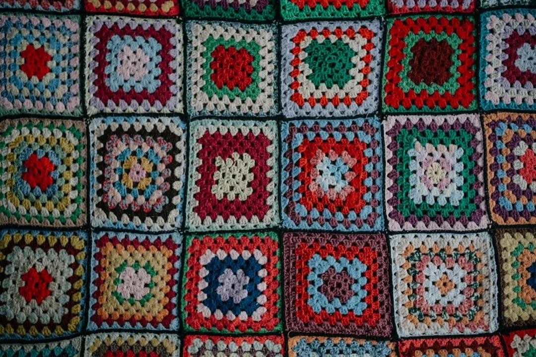 A quilt with crochet squares in multiple rainbow colors.