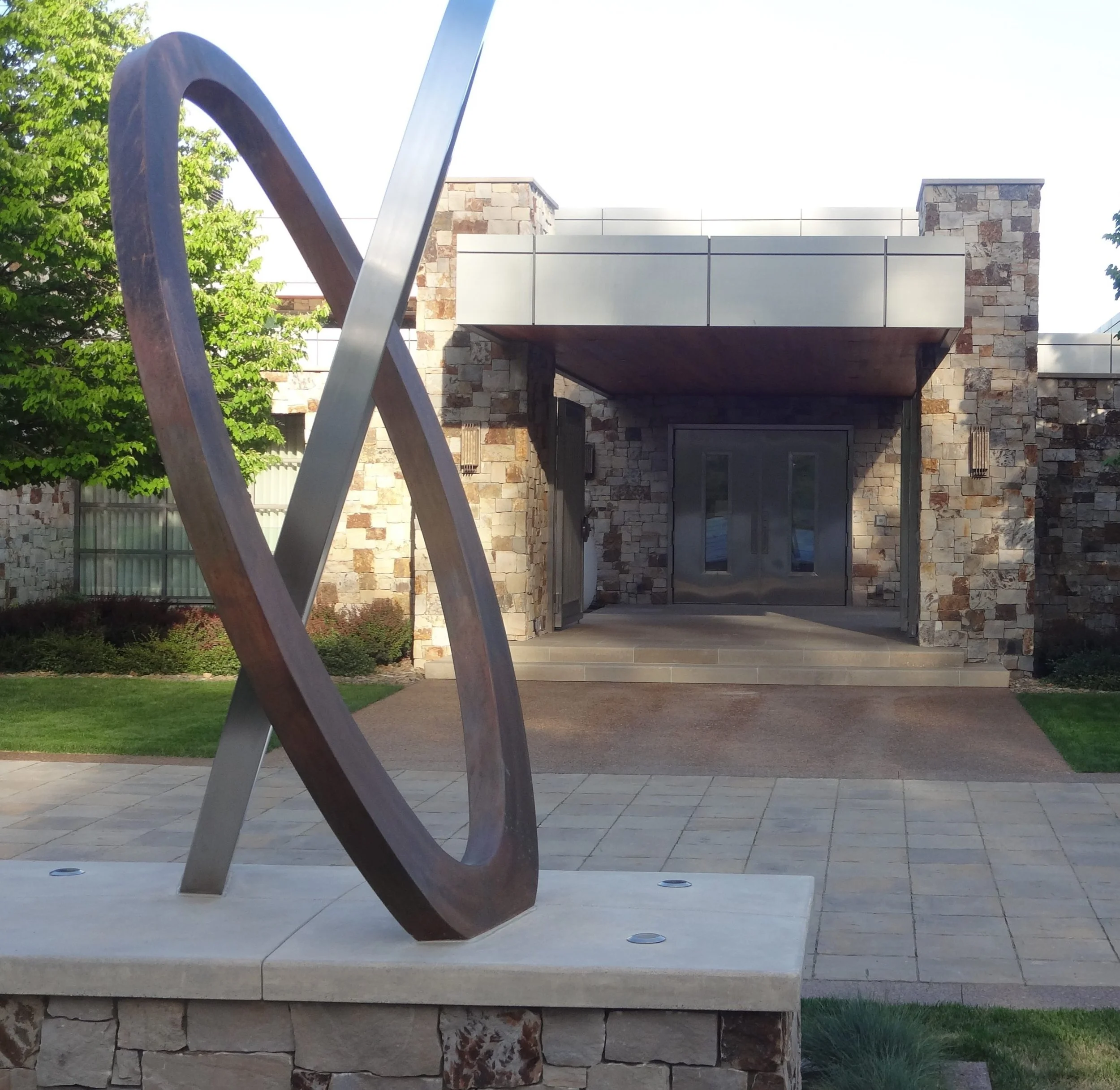 Modern stone building entrance with metal sculpture in foreground