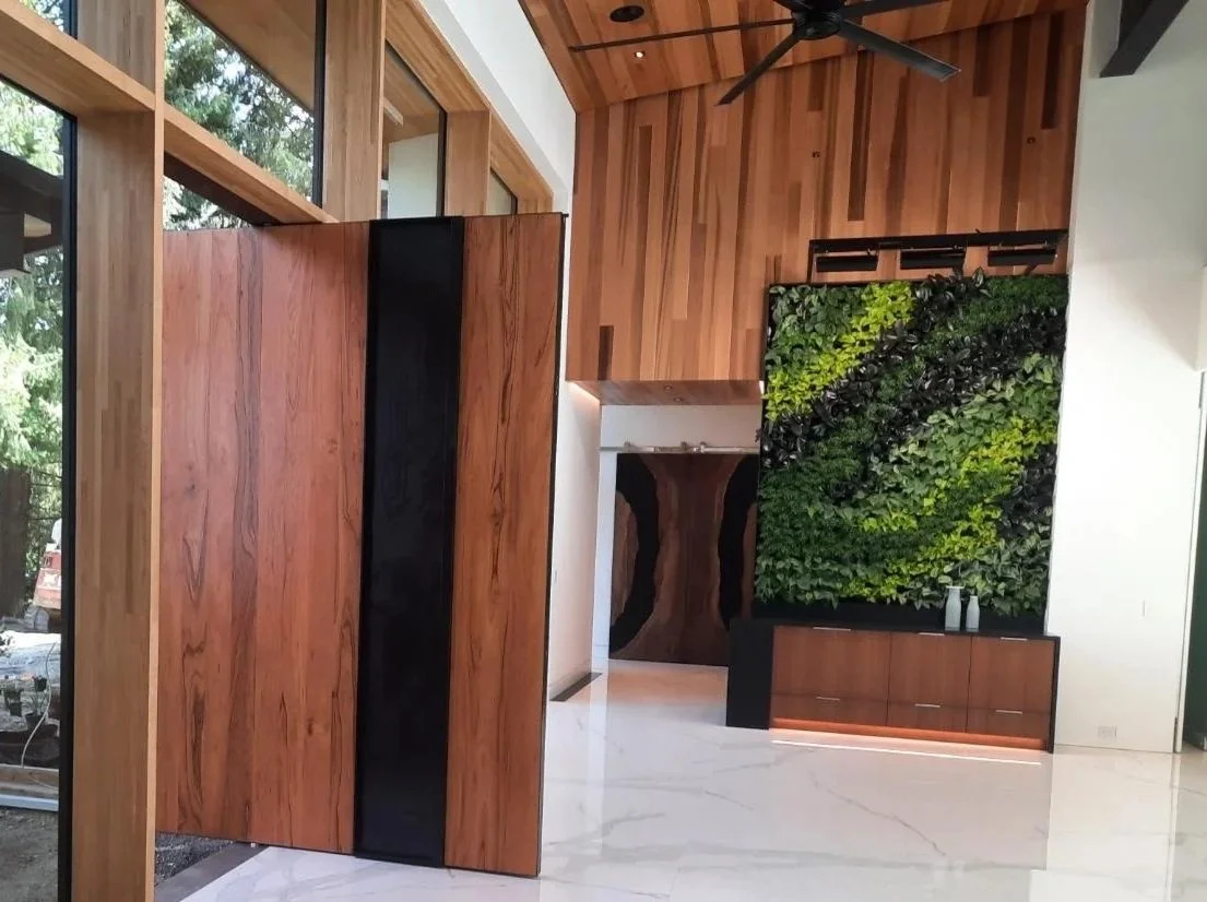 Modern interior with wooden paneling, green living wall, ceiling fan, marble flooring, and large windows.