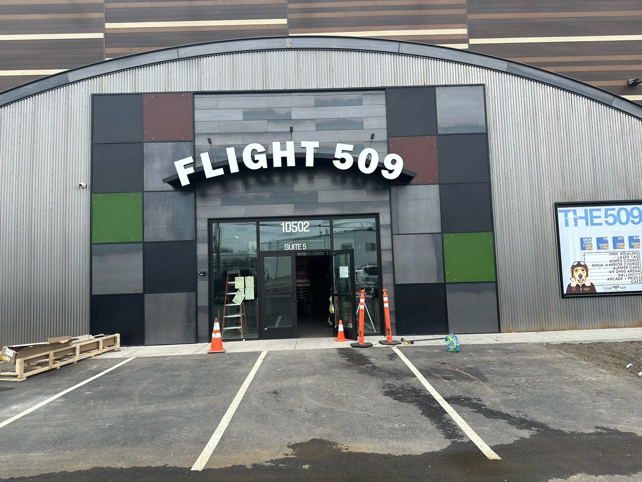 Front of a building with a sign that reads Flight 509, with parking spaces and construction cones in front.