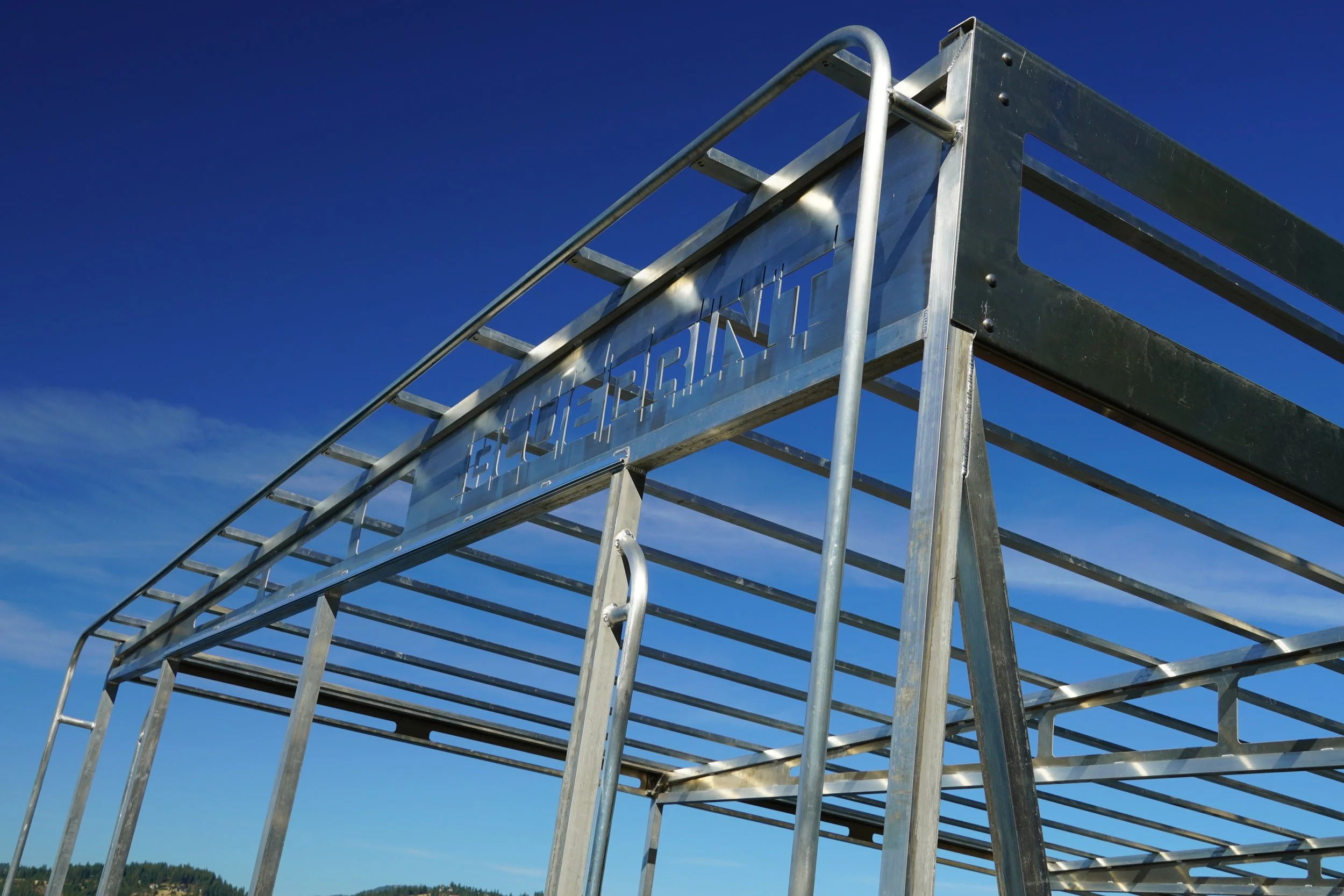 Close-up of a metallic structure with a sign reading 'ELEVATED TRAIL' against a clear blue sky.