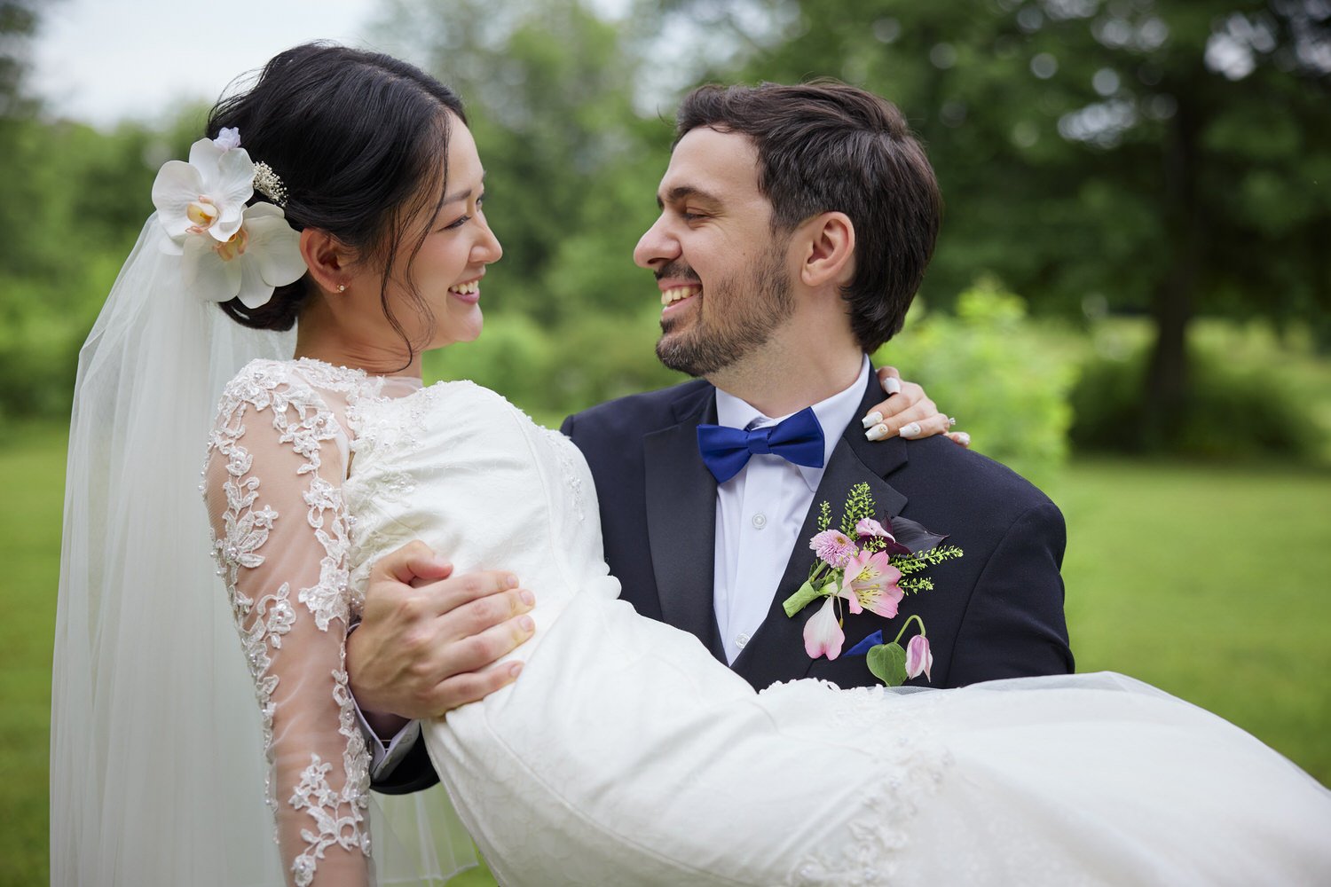 A groom carrying his bride in a field.