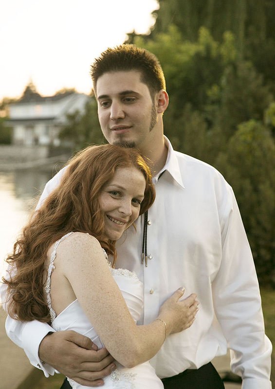A portrait of a bride and groom holding each other in front of a lake at Stewart Hall in Pointe-Claire.