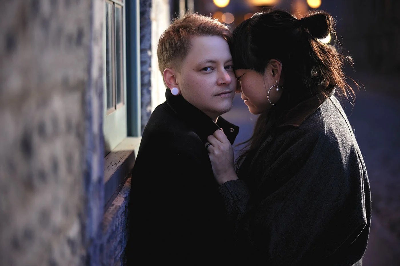 A photo of a man and woman holding each other in a dark alley.