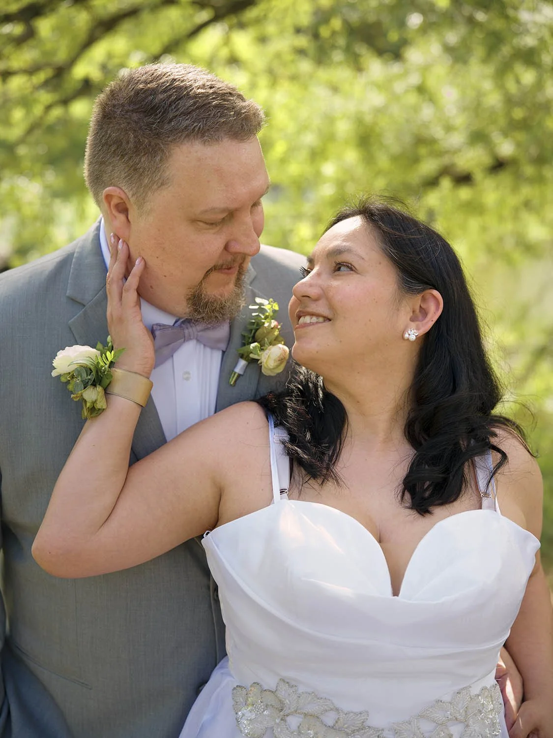 A close-up portrait of a bride and groom in a natural setting.