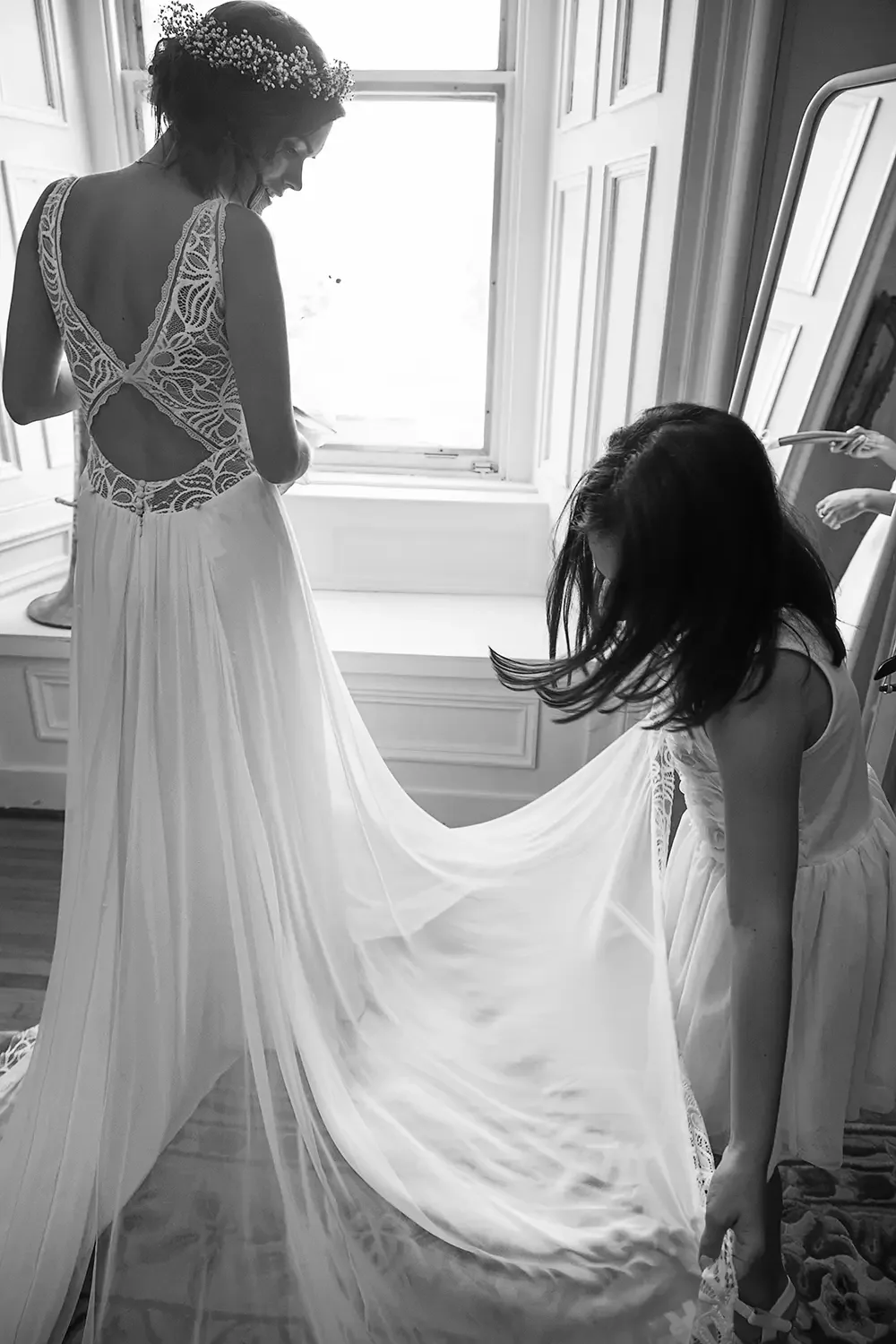 A photo of a young girl helping a bride adjust her dress before her wedding at Forest and Stream club in Dorval, near Montreal.