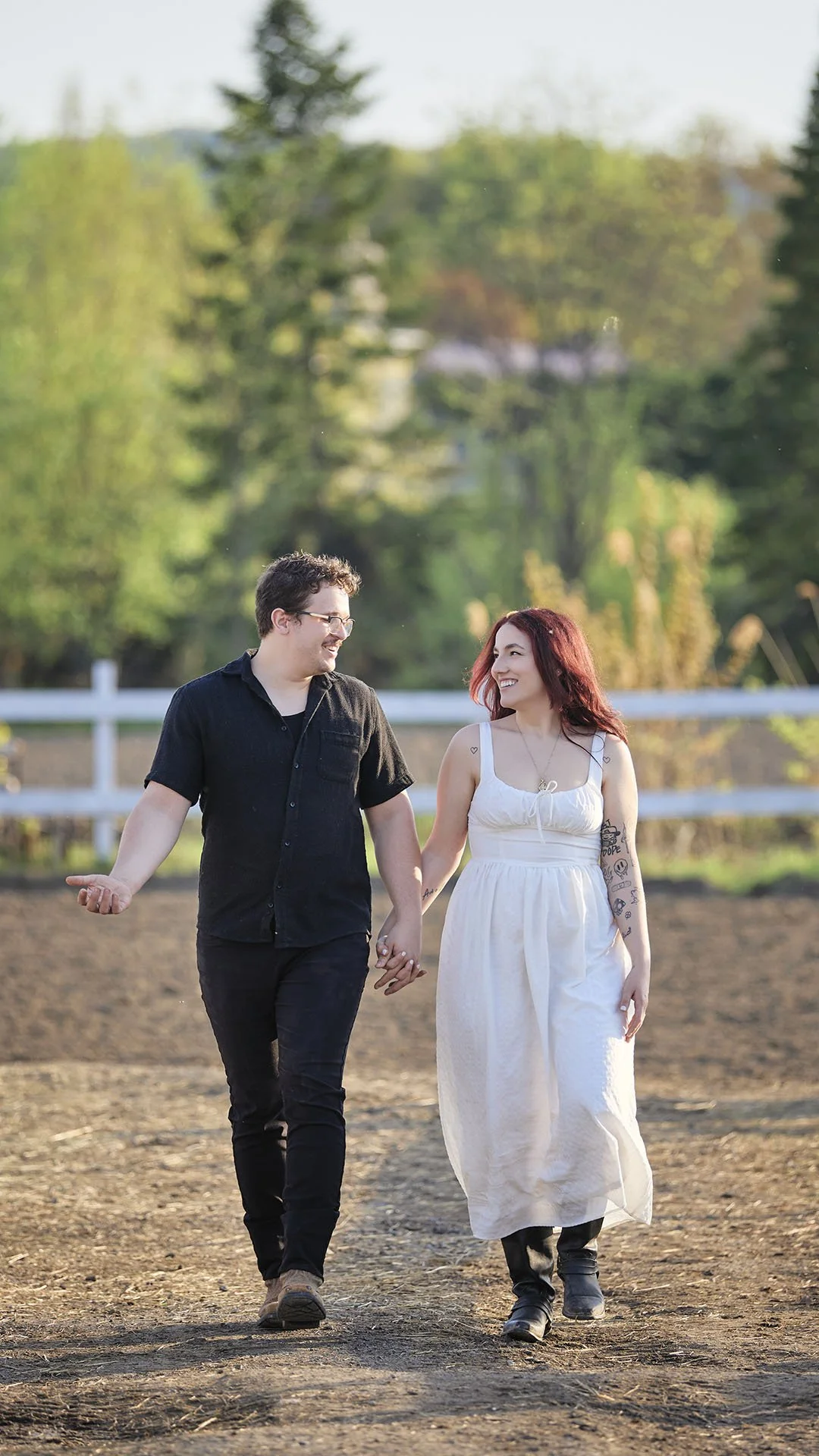 A photo of a man and a woman holding hands while walking on a ranch.