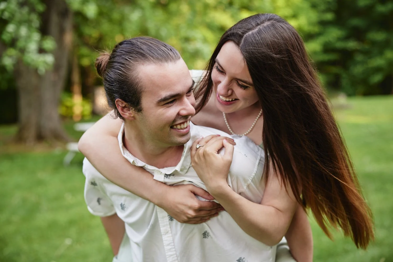 A candid portrait of a young man and woman in a park with trees.