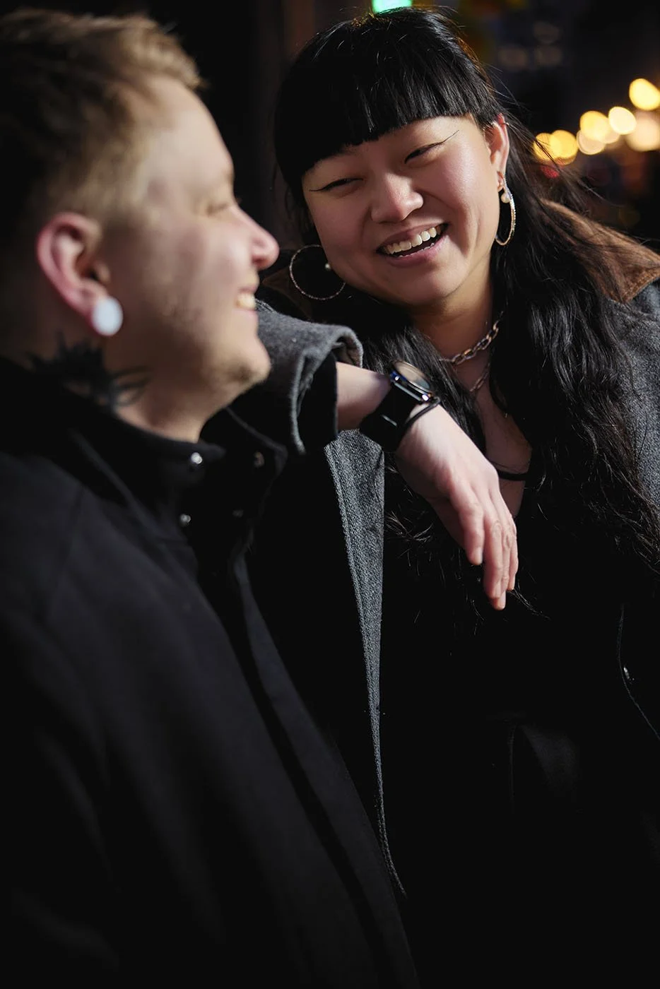 A portrait of a man and woman laughing at night in Old Montreal.