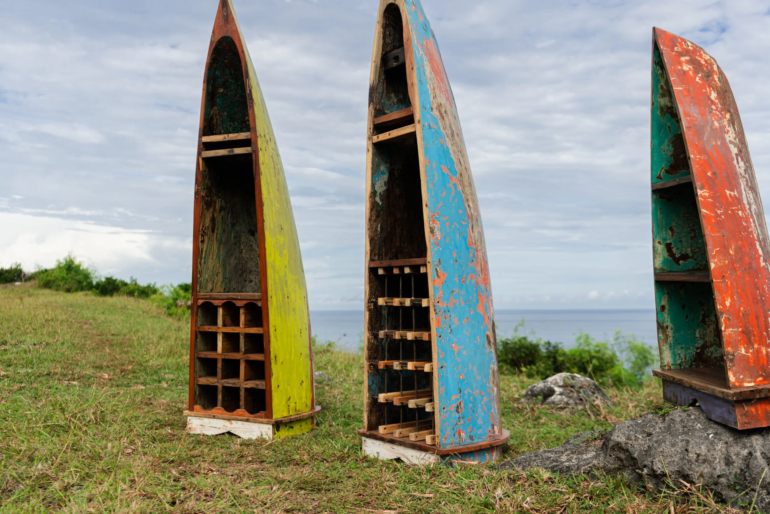 Reclaimed wooden boats transformed into unique wine rack and shelving units, set against a coastal backdrop at PAAT Designs.