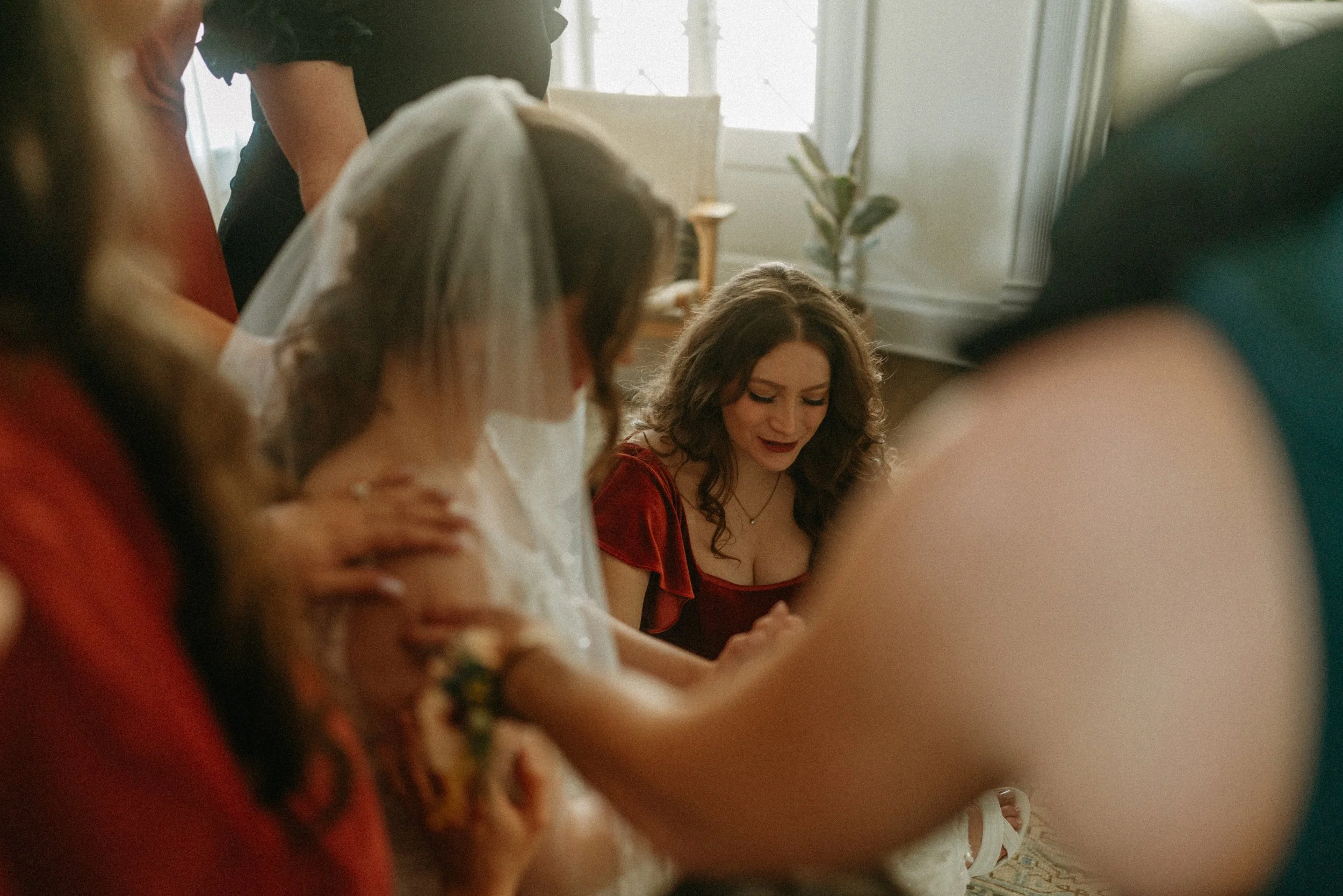 documentary style wedding photography candid of the bride being prayed over by her bridesmaids in the light airy bridal suite at The Grand Lady in manor tx just outside of austin