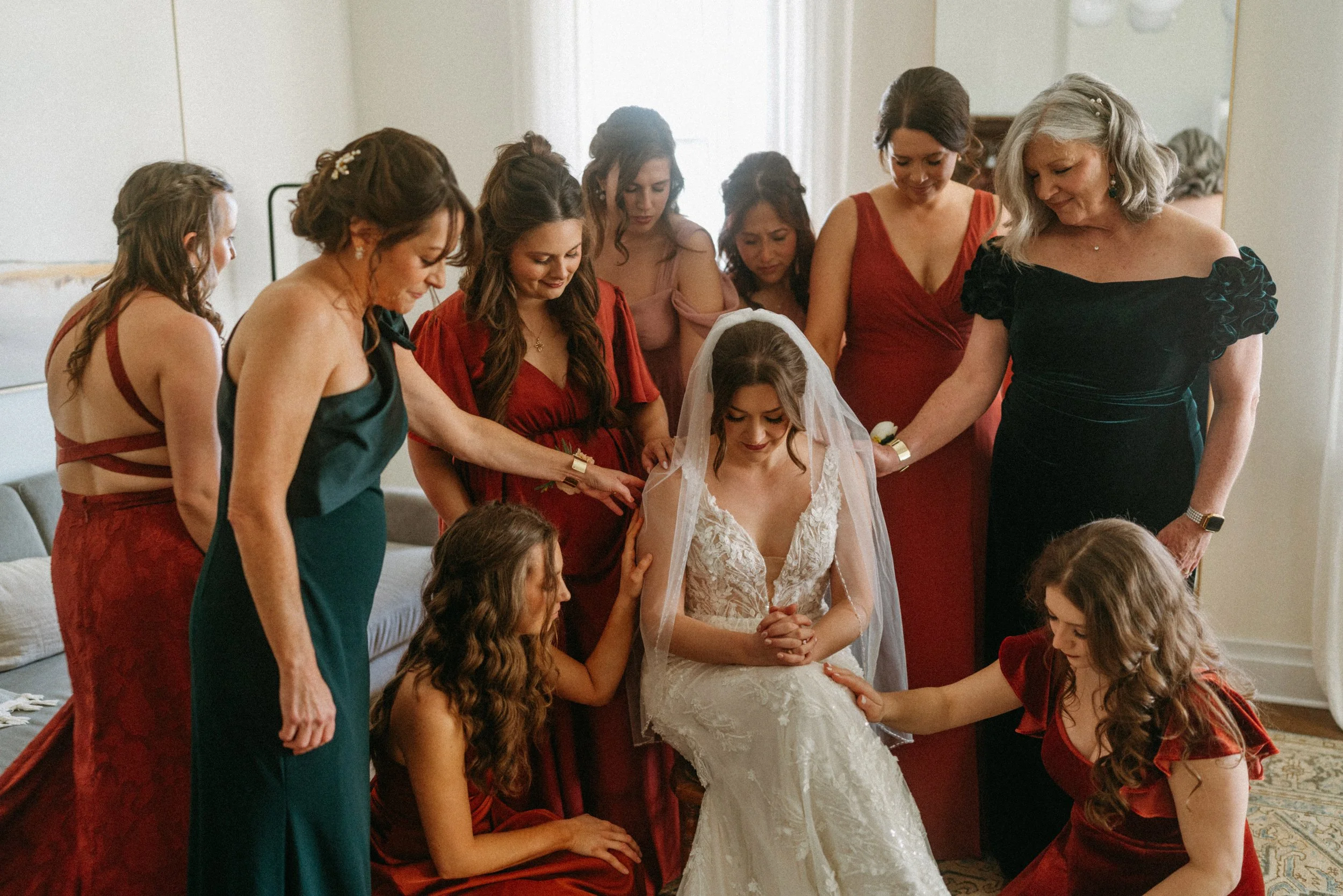 documentary style wedding photography candid of the bride being prayed over by her bridesmaids in the light airy bridal suite at The Grand Lady in manor tx just outside of austin