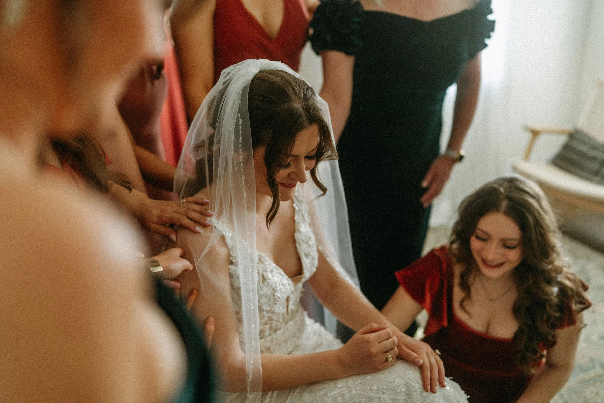 documentary style wedding photography candid of the bride being prayed over by her bridesmaids in the light airy bridal suite at The Grand Lady in manor tx just outside of austin