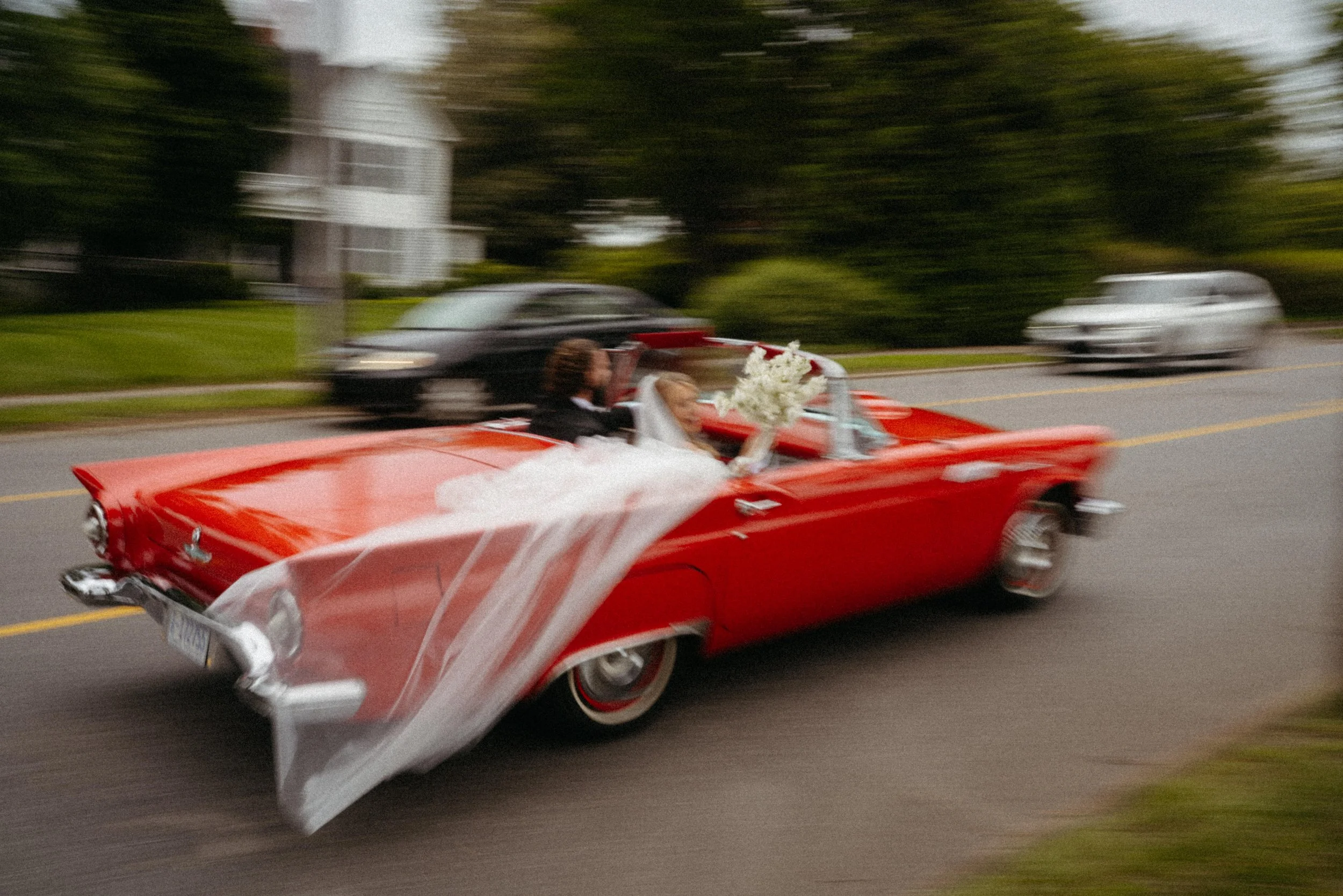 bride smiling in vintage red convertible wedding getaway car