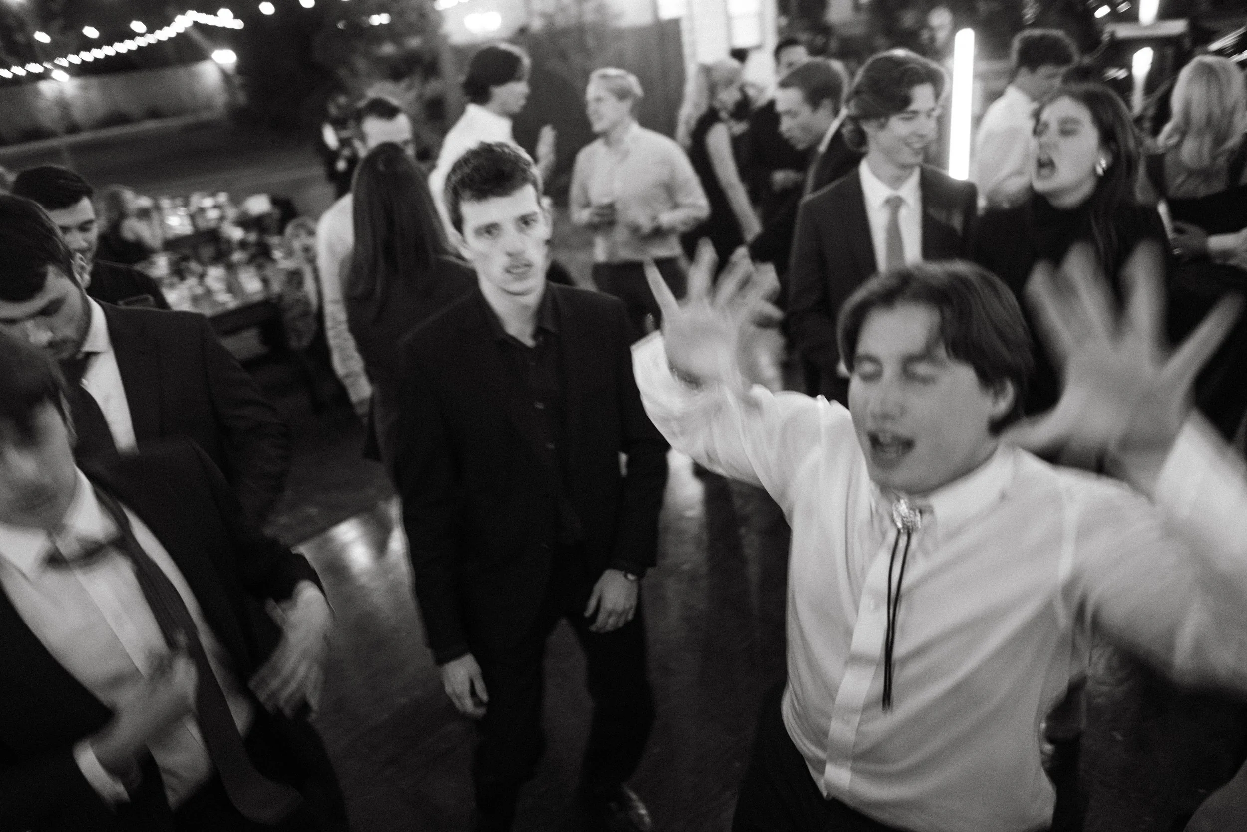 Wedding guests raising hands on the dance floor with live band playing.