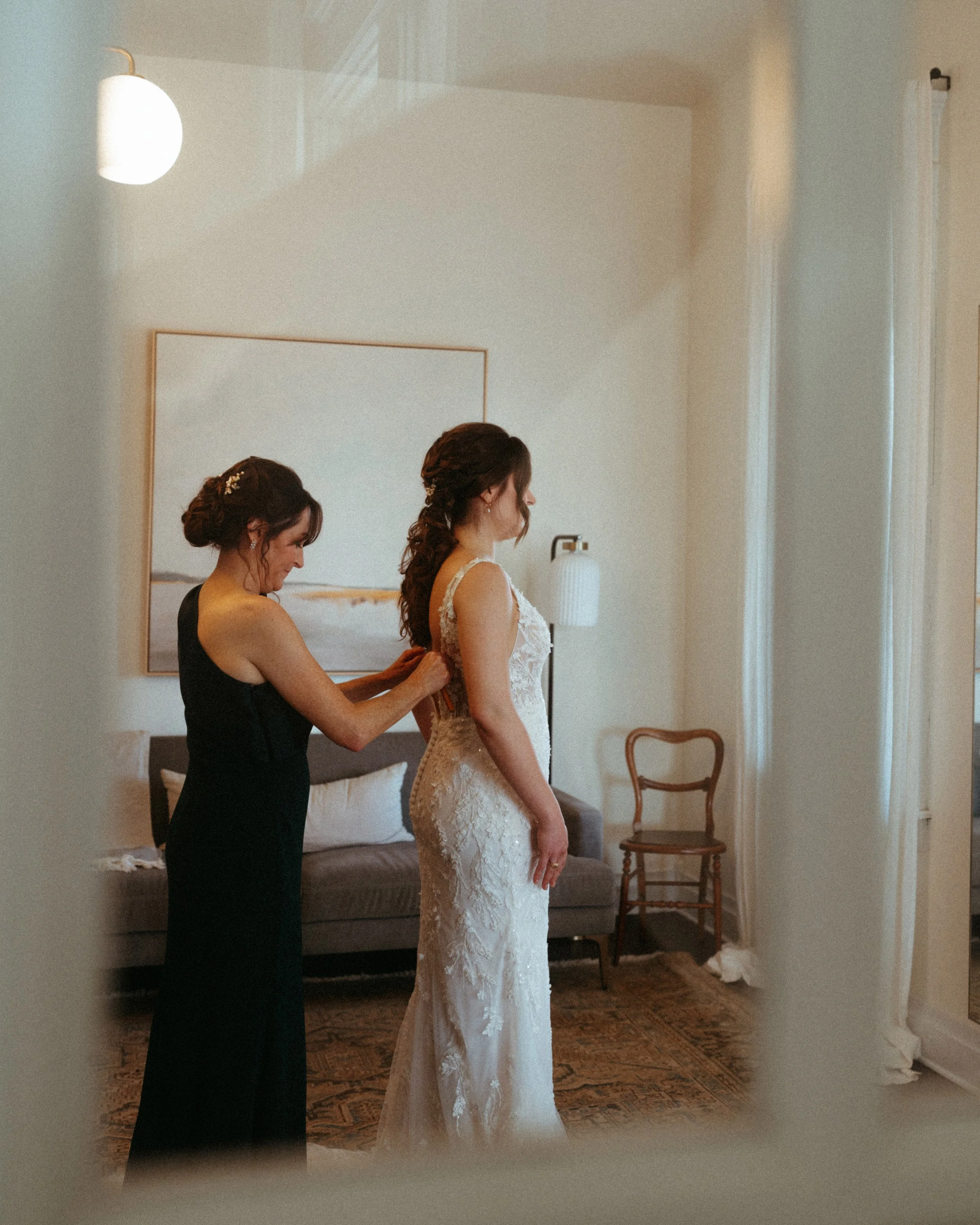 candid of Mother of the Bride getting helping bride get into her bridal gown in mansion suite at The Grand Lady in manor tx just outside of austin