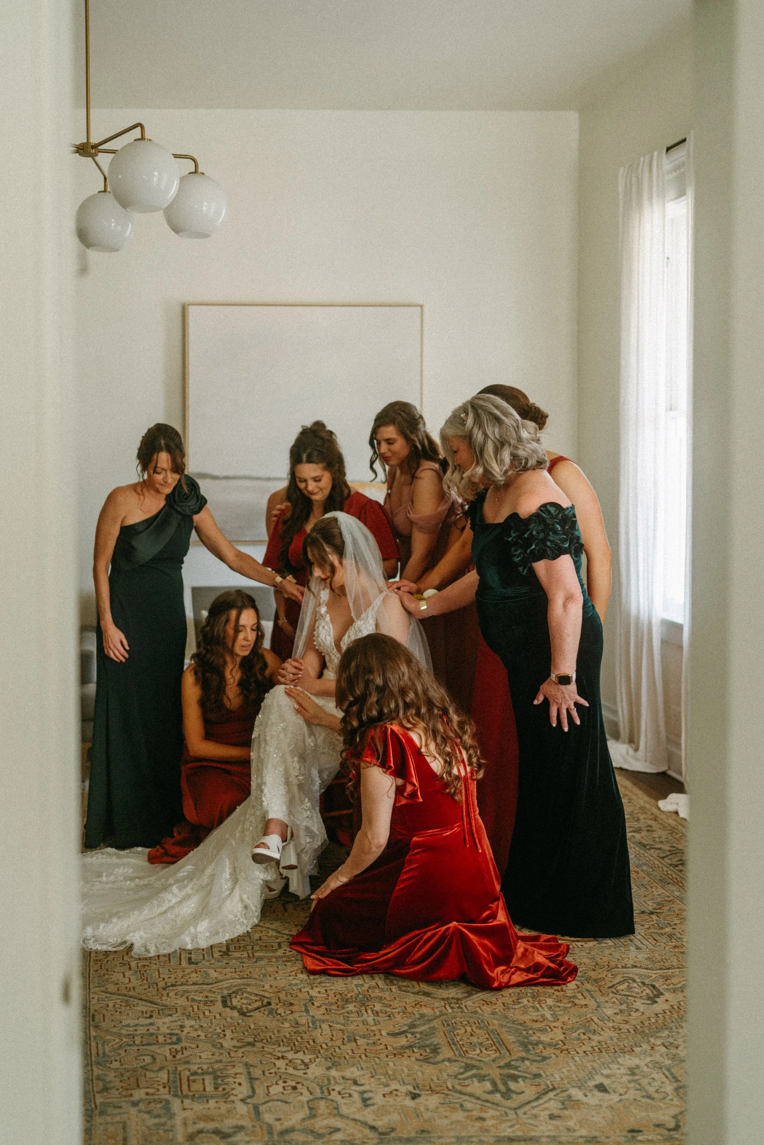 documentary style wedding photography candid of the bride being prayed over by her bridesmaids in the light airy bridal suite at The Grand Lady in manor tx just outside of austin