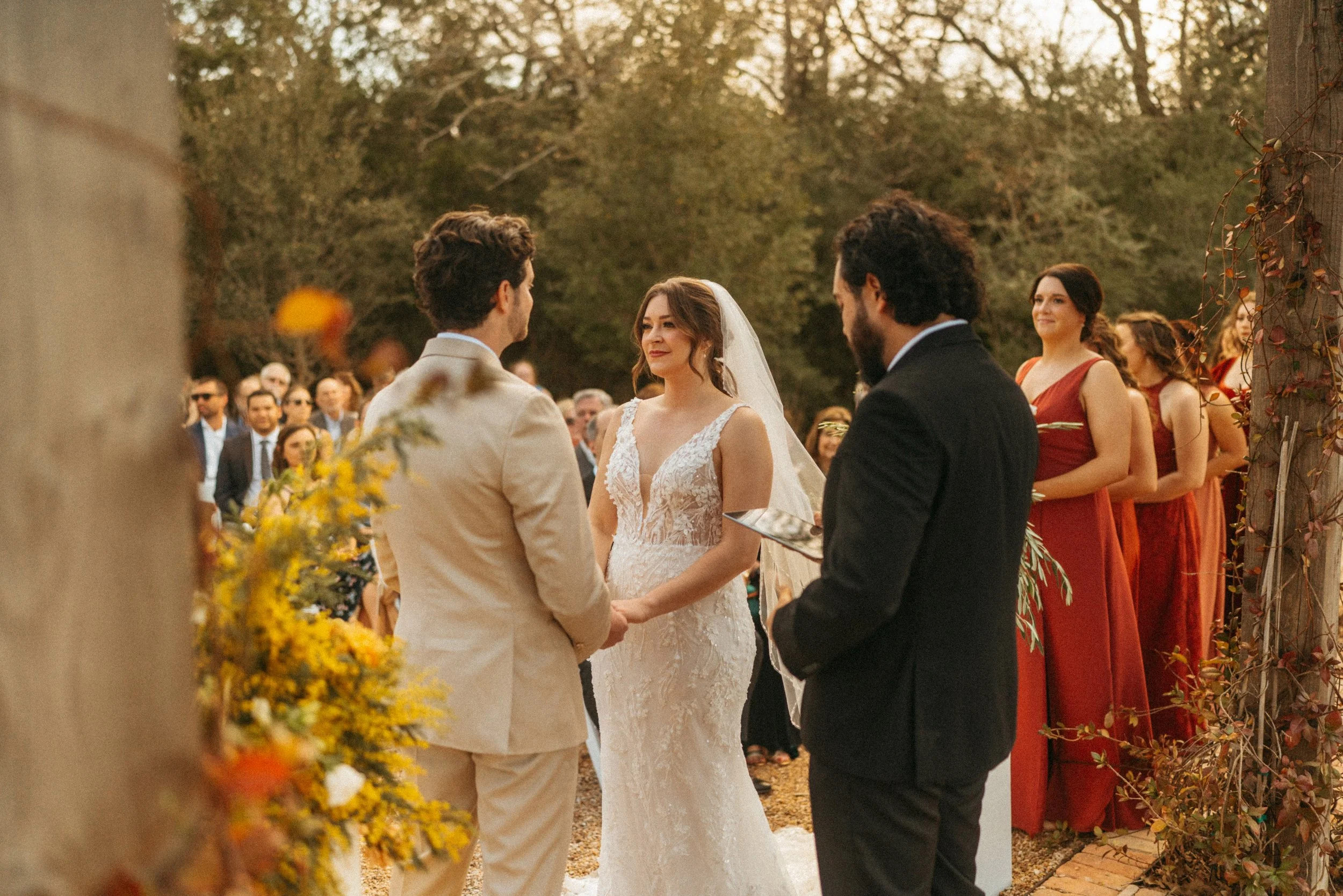 Couple holding hands during their Austin wedding ceremony at The Grand Lady pergola with beautiful florals from Golden Dream Florals