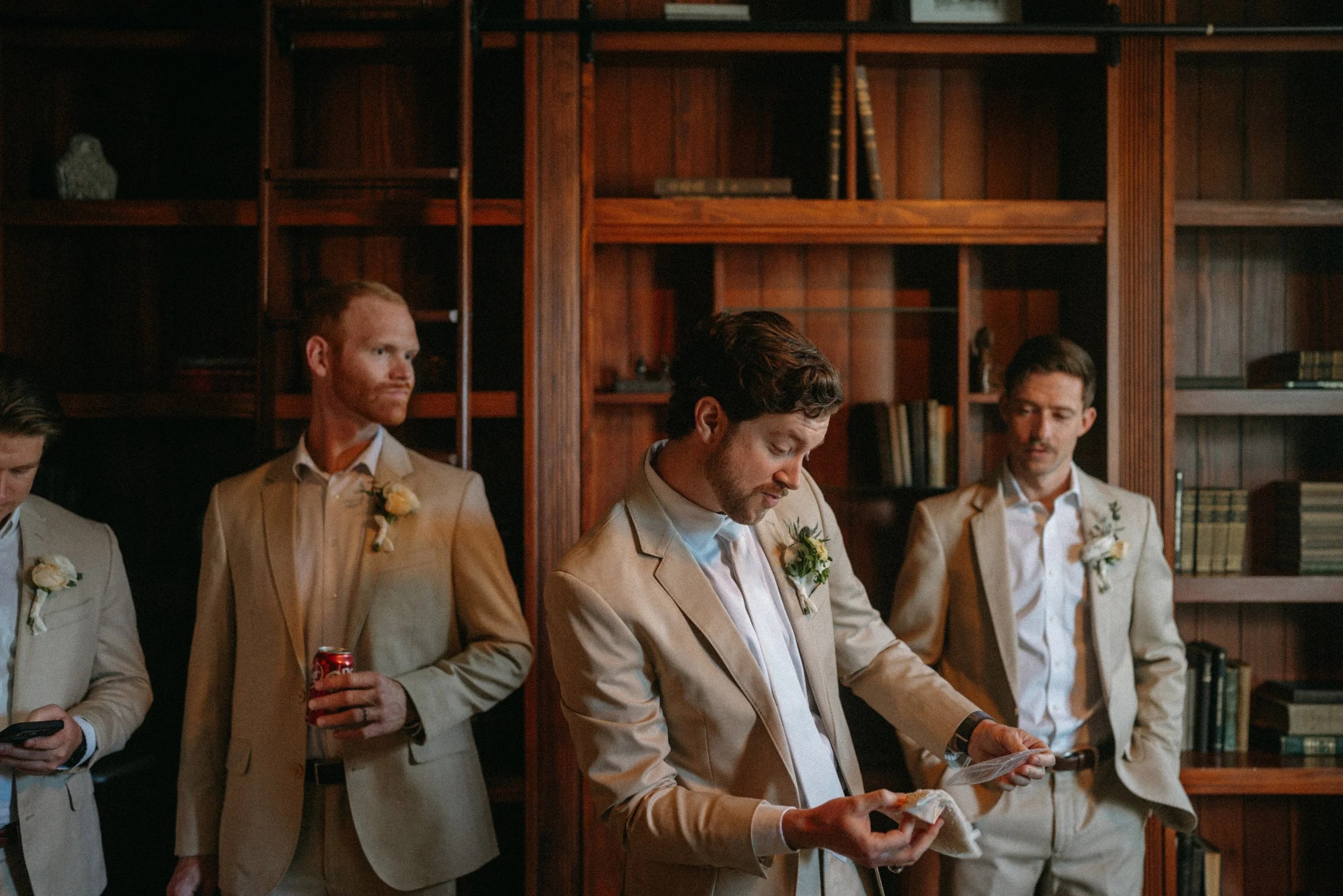 documentary style wedding photography candid of the groom and groomsmen in the old money library at The Grand Lady in manor tx just outside of austin