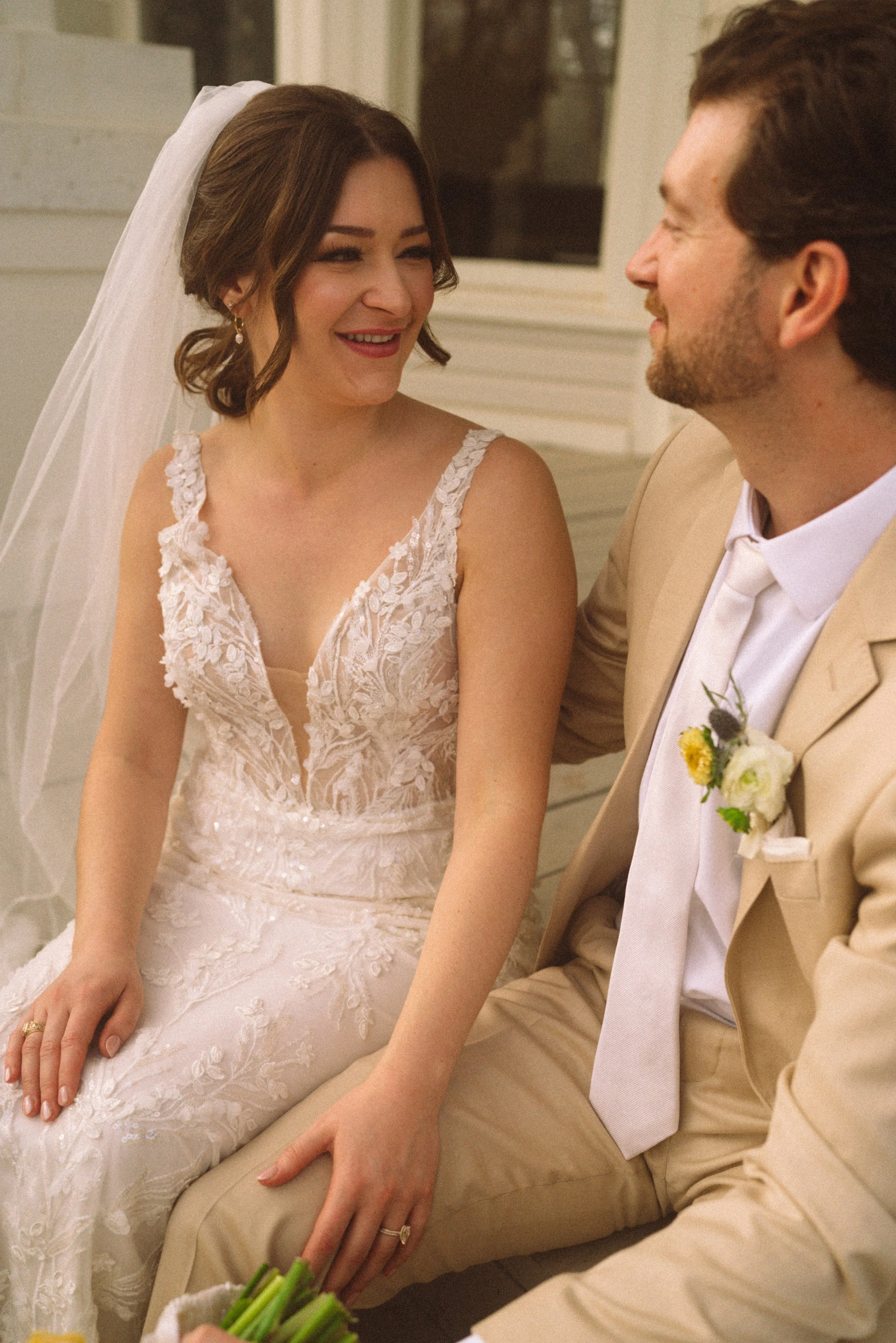 Bride and groom sitting in front of The Grand Lady historic mansion