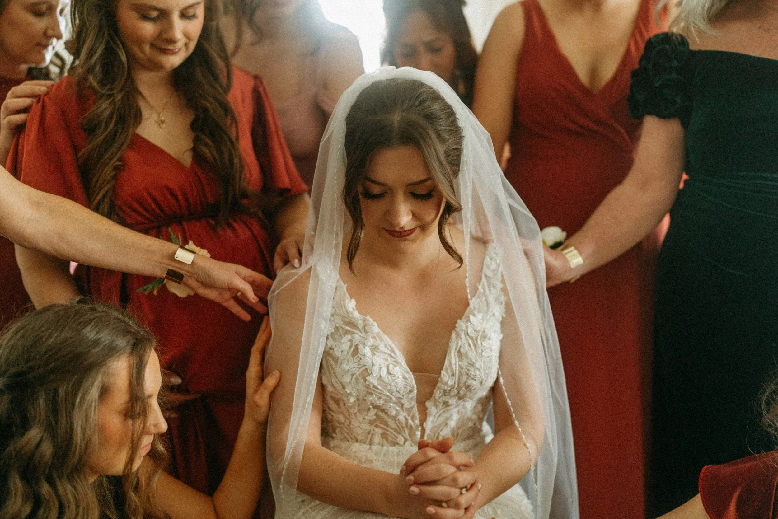 documentary style wedding photography candid of the bride being prayed over by her bridesmaids in the light airy bridal suite at The Grand Lady in manor tx just outside of austin